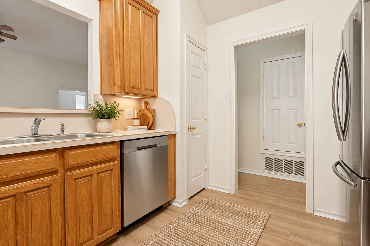 Kitchen featuring wood cabinetry, stainless steel dishwasher, double basin sink with chrome faucet, and wood-finish flooring
