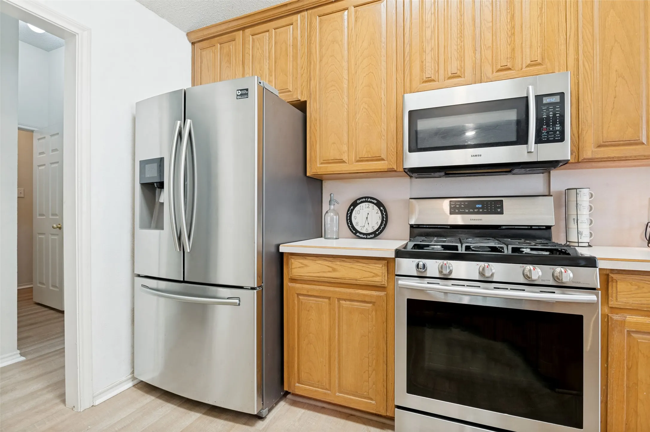 Kitchen featuring wood-finish cabinetry, stainless steel refrigerator, stainless steel microwave, stainless steel gas range, and light-toned countertops