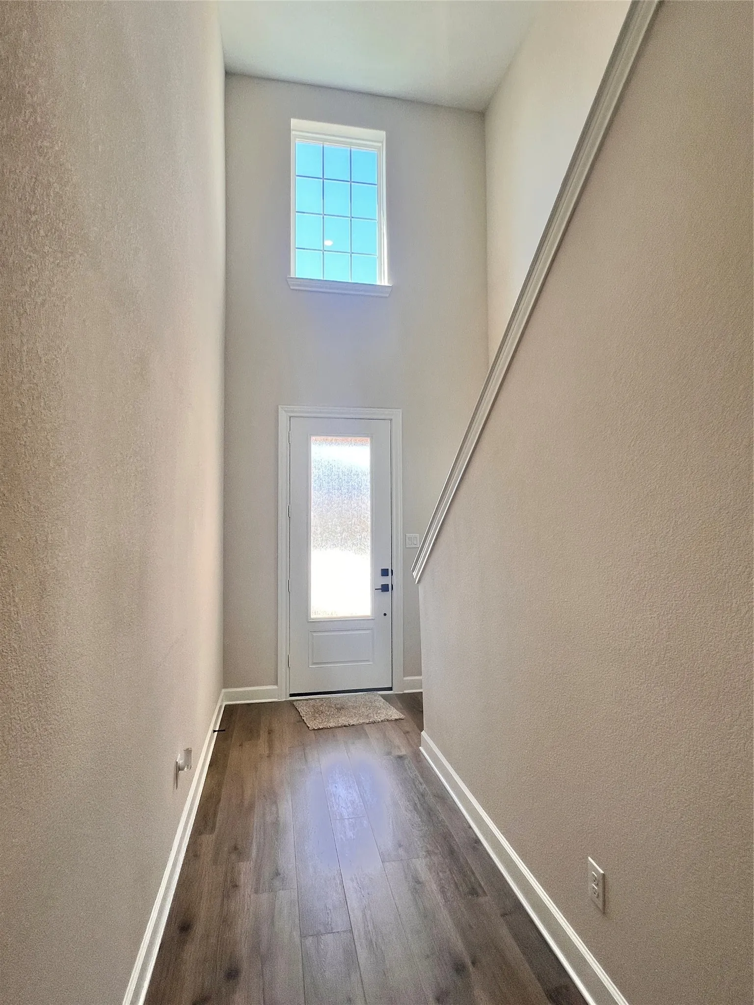 Entryway featuring a white paneled door with frosted glass, wood-finish flooring, and a high transom window