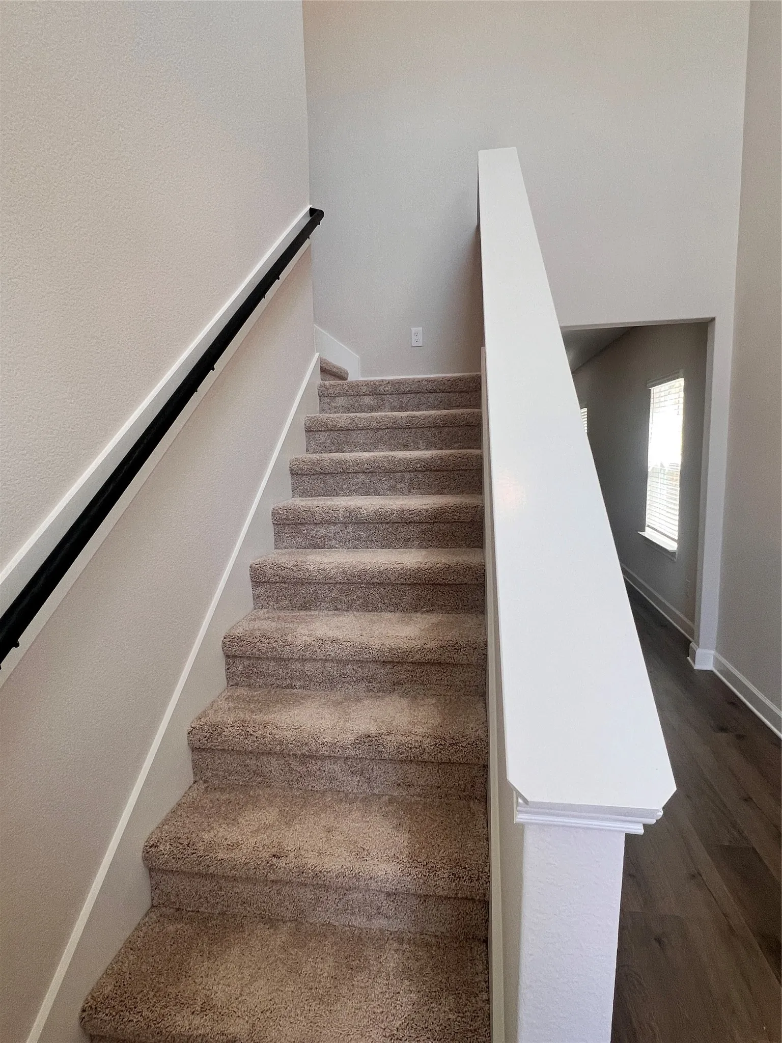Carpeted staircase with a black handrail and white balustrade
