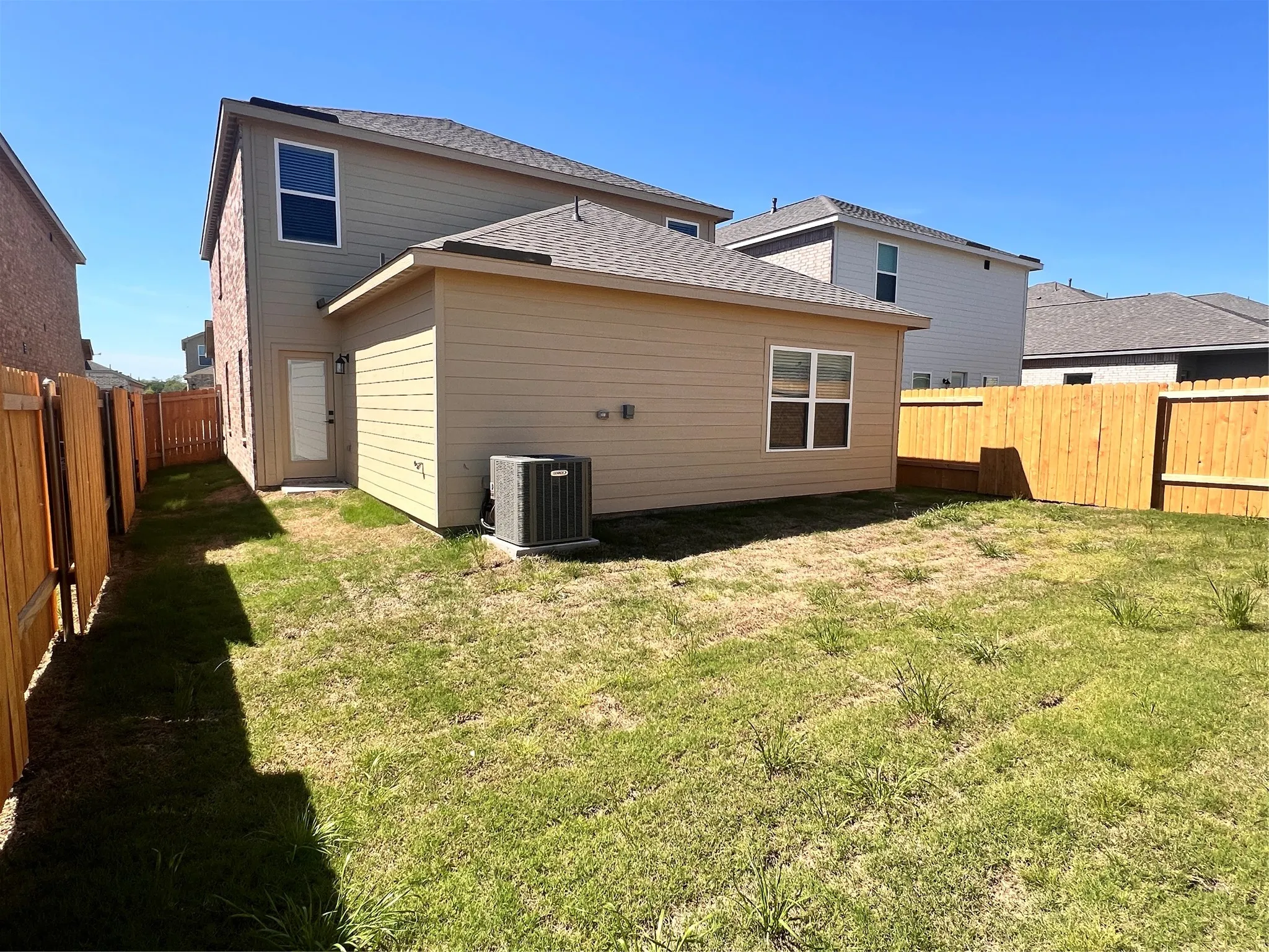 Fenced backyard featuring a rear entry door and a ground-level window