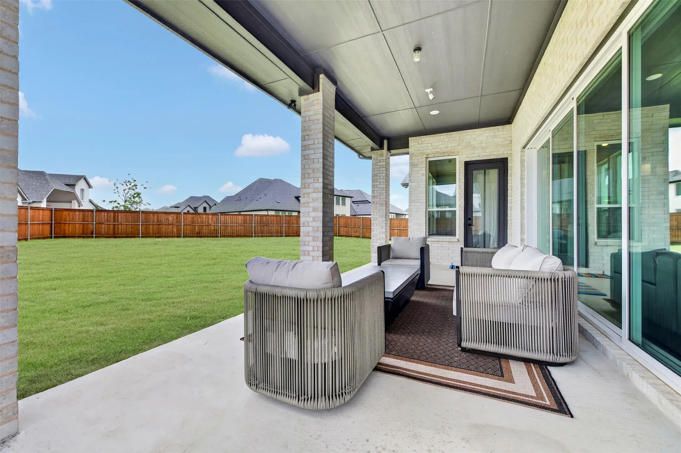 Covered patio with brick columns, smooth concrete flooring, and recessed lighting