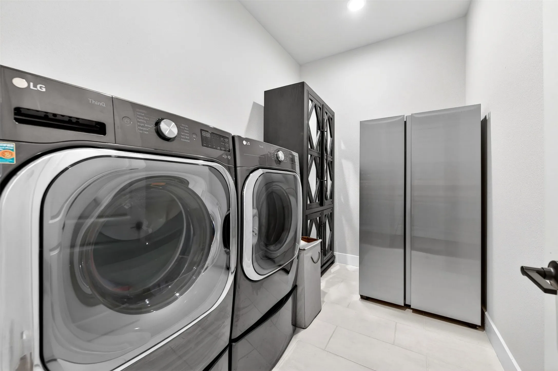 Dedicated utility space featuring light-toned flooring, tall white walls, and a recessed ceiling light
