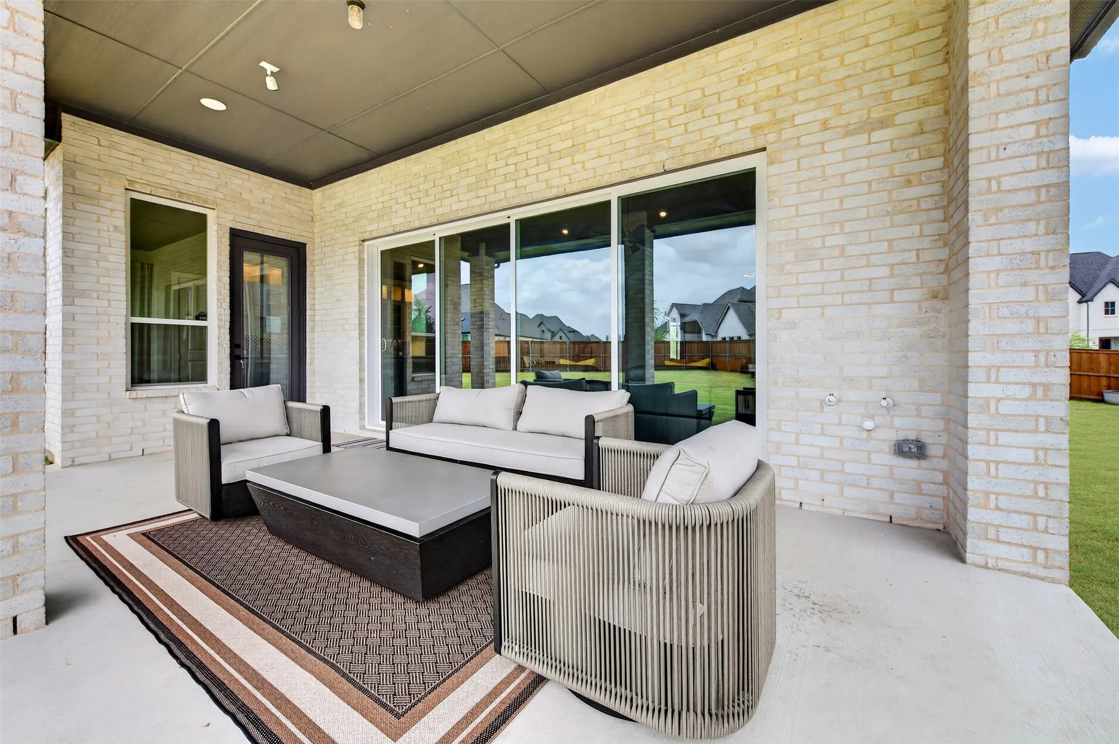 Covered patio featuring a painted ceiling with recessed lighting, light-colored brick exterior, and a large sliding glass door