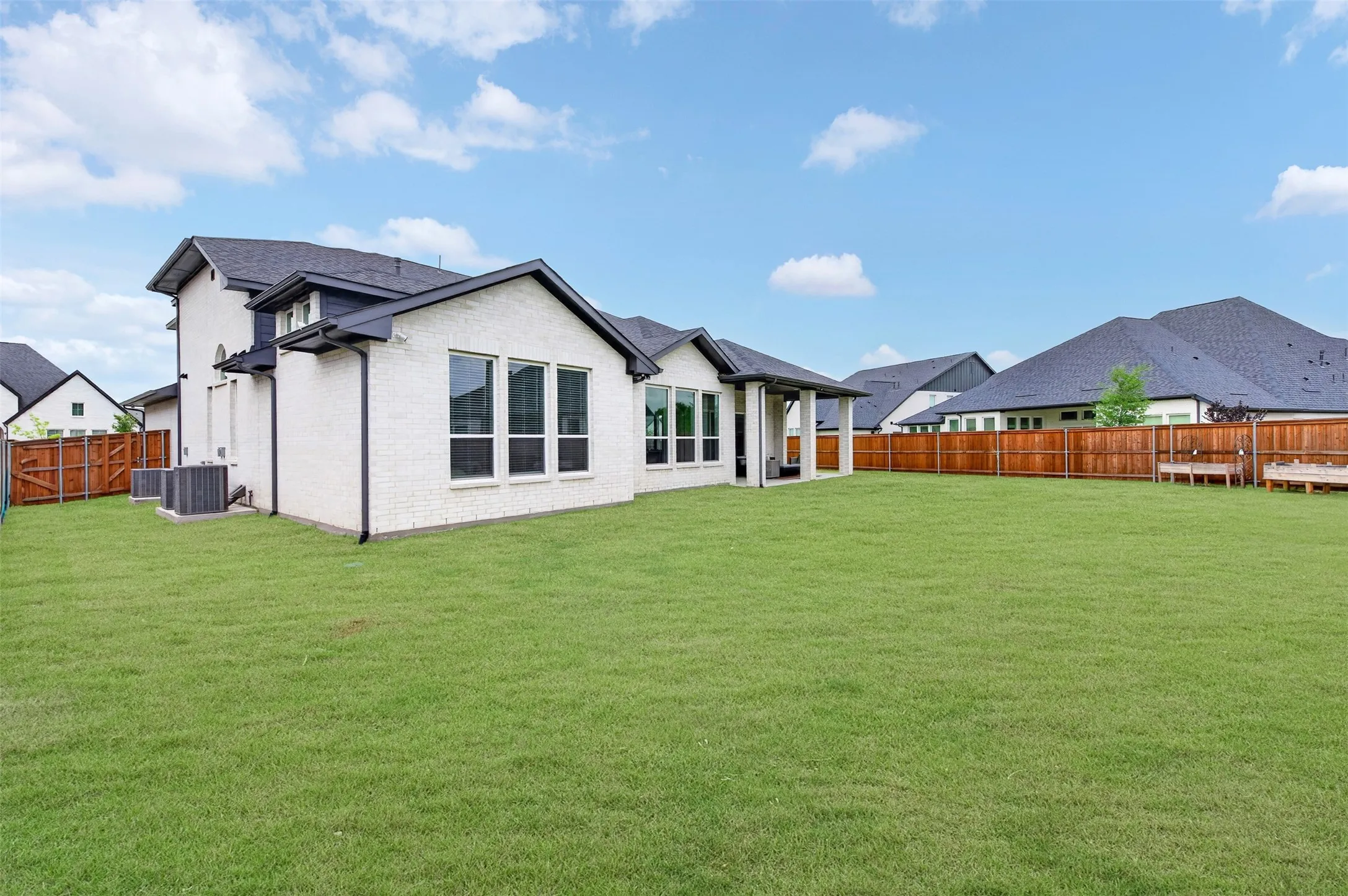 Expansive green lawn with a white brick exterior and a dark-pitched roof