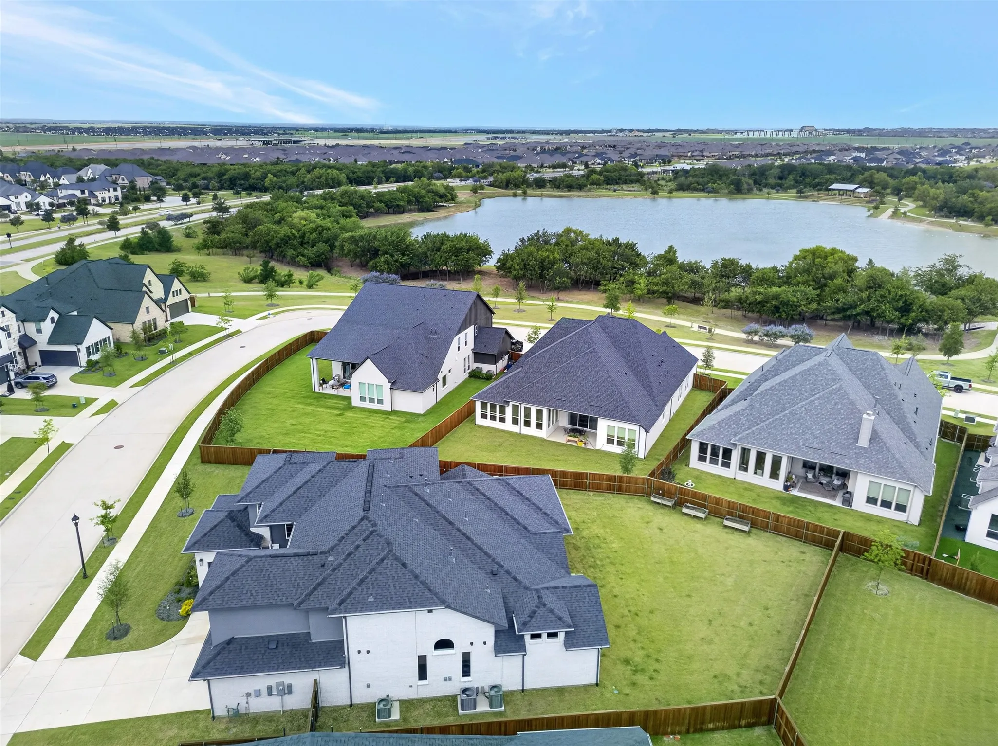 Curved street frontage, expansive green space, manicured lawns, private fenced yards, and a prominent water feature