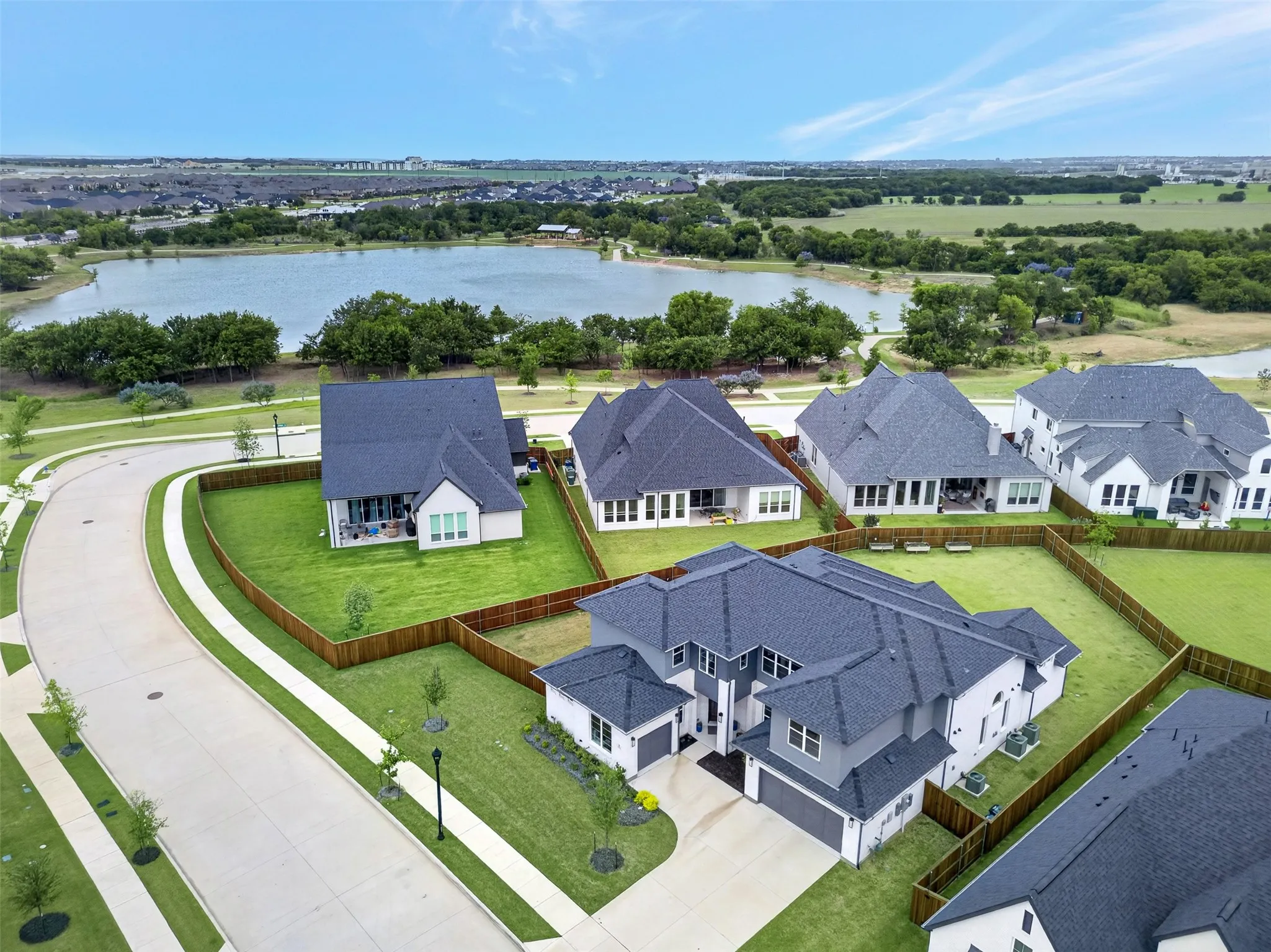Expansive aerial showcasing multiple properties, a large body of water, and surrounding green spaces