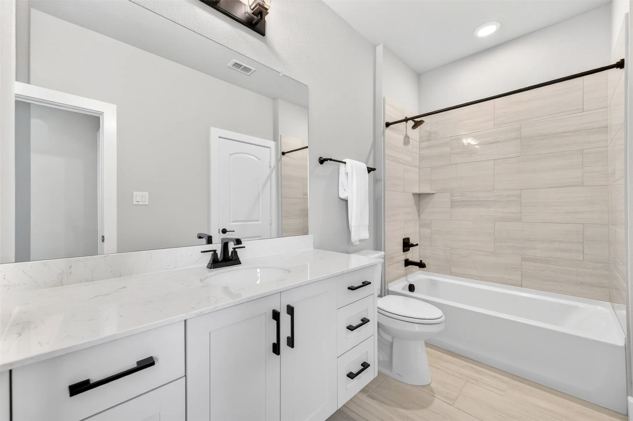 White vanity with a quartz countertop, rectangular sink, and matte black fixtures