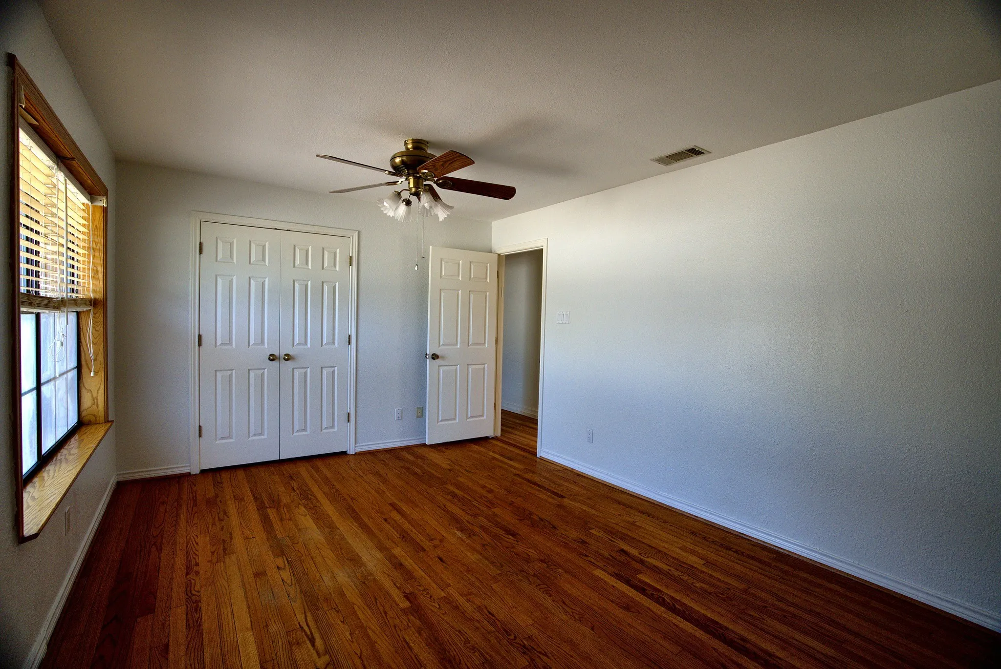 Hardwood flooring, window with blinds, ceiling fan with integrated lighting, paneled closet doors, and a neutral wall finish