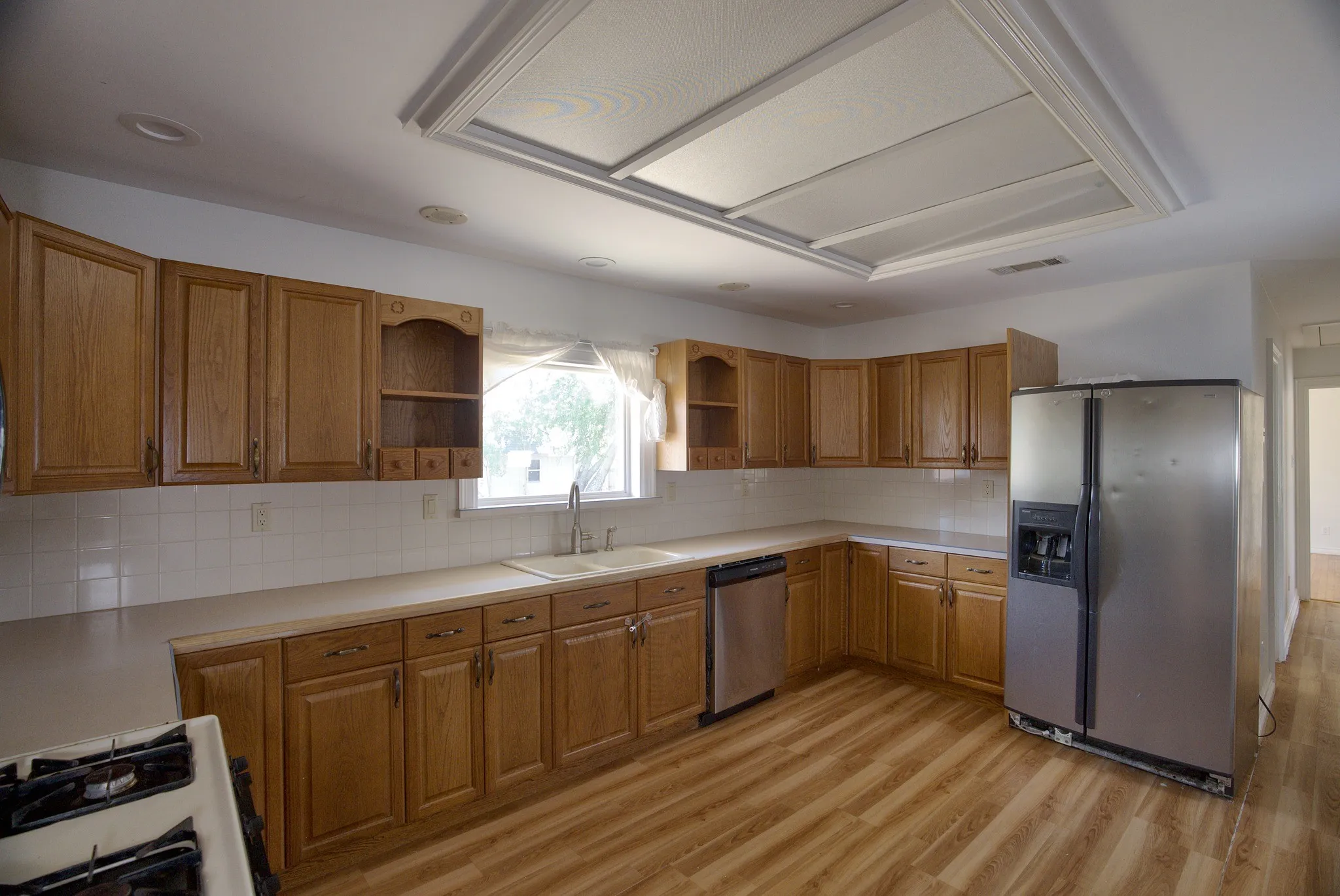 Kitchen with wood-finish flooring, recessed lighting, wood cabinetry, stainless steel dishwasher, and a side-by-side refrigerator