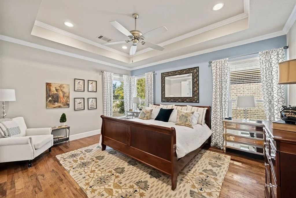 Tray ceiling with recessed lighting, wood-finish flooring, and crown molding