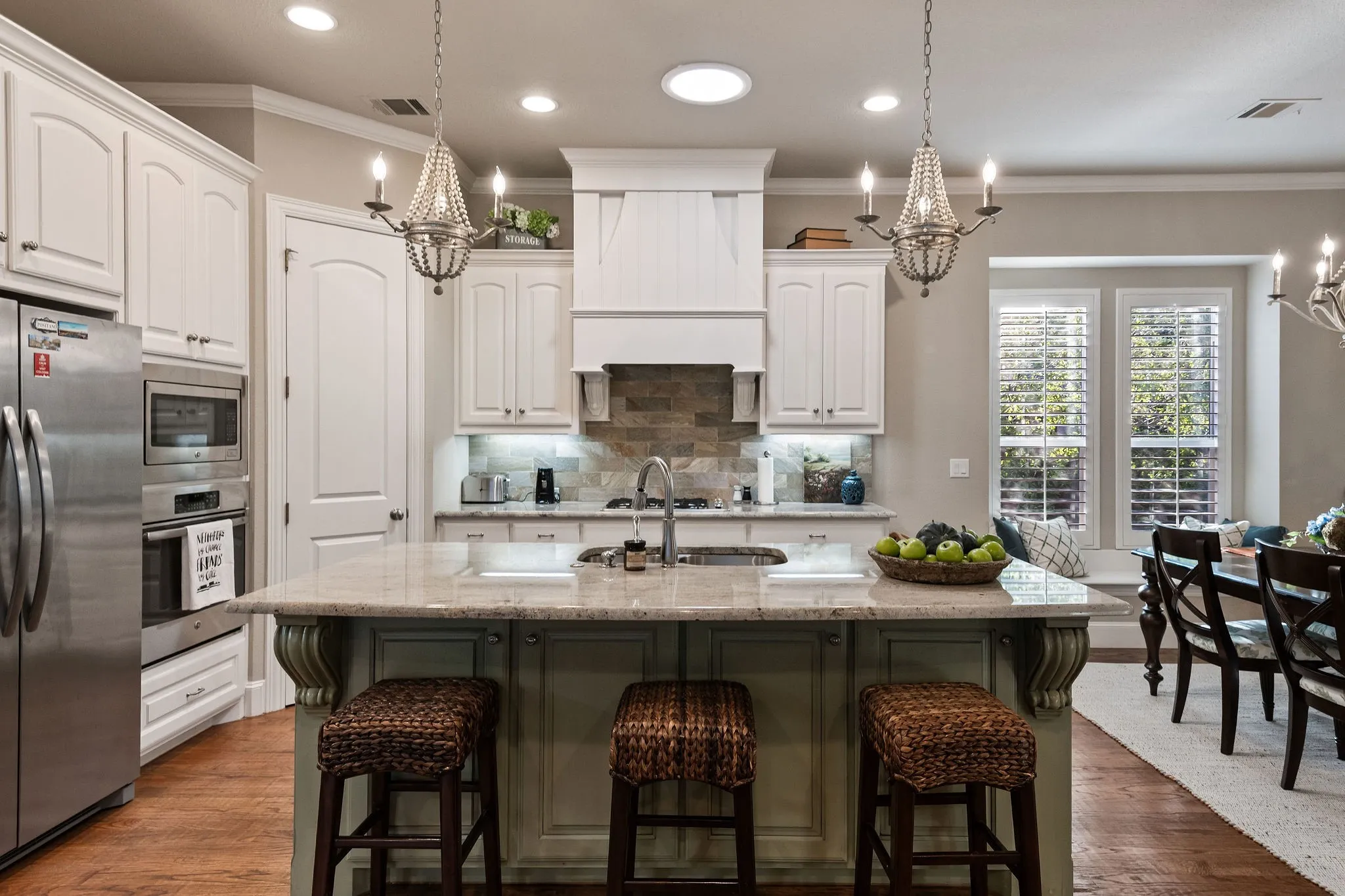 Kitchen featuring a central island with countertop seating, white cabinetry, stainless steel appliances, a stone tile backsplash, and a built-in window bench