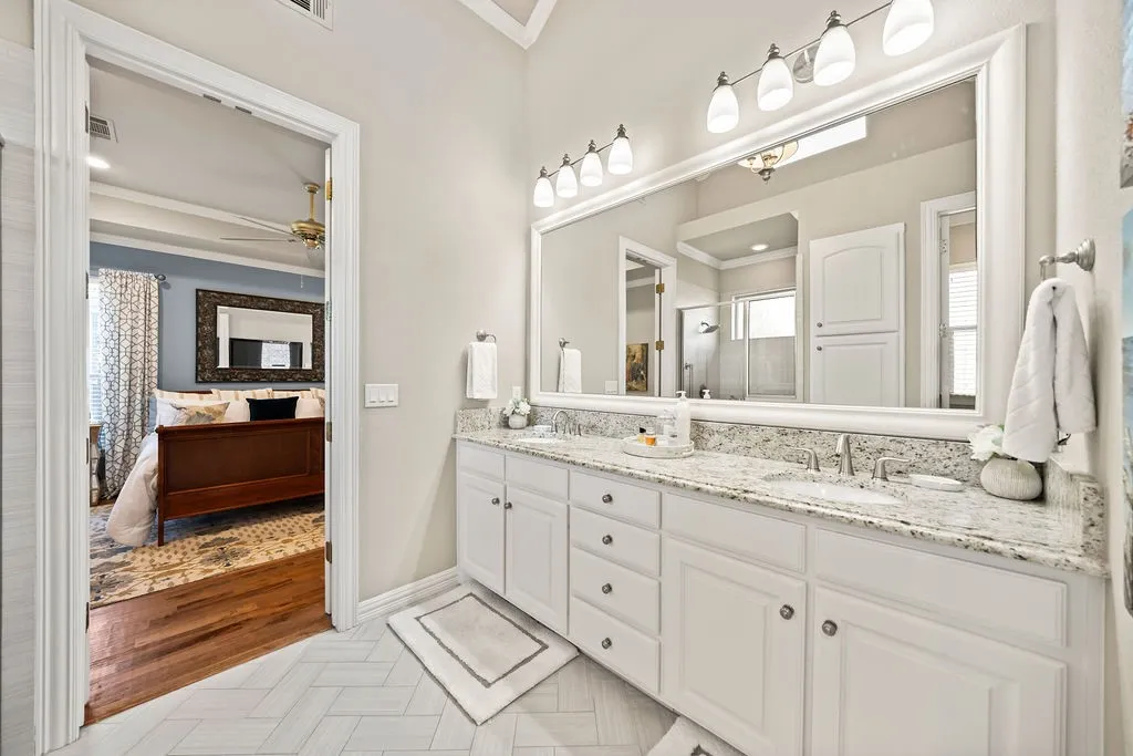 Double vanity with white cabinetry, granite countertop, and dual sinks