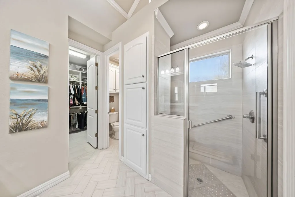 Glass-enclosed shower with a rainfall showerhead, grab bar, and tiled surround