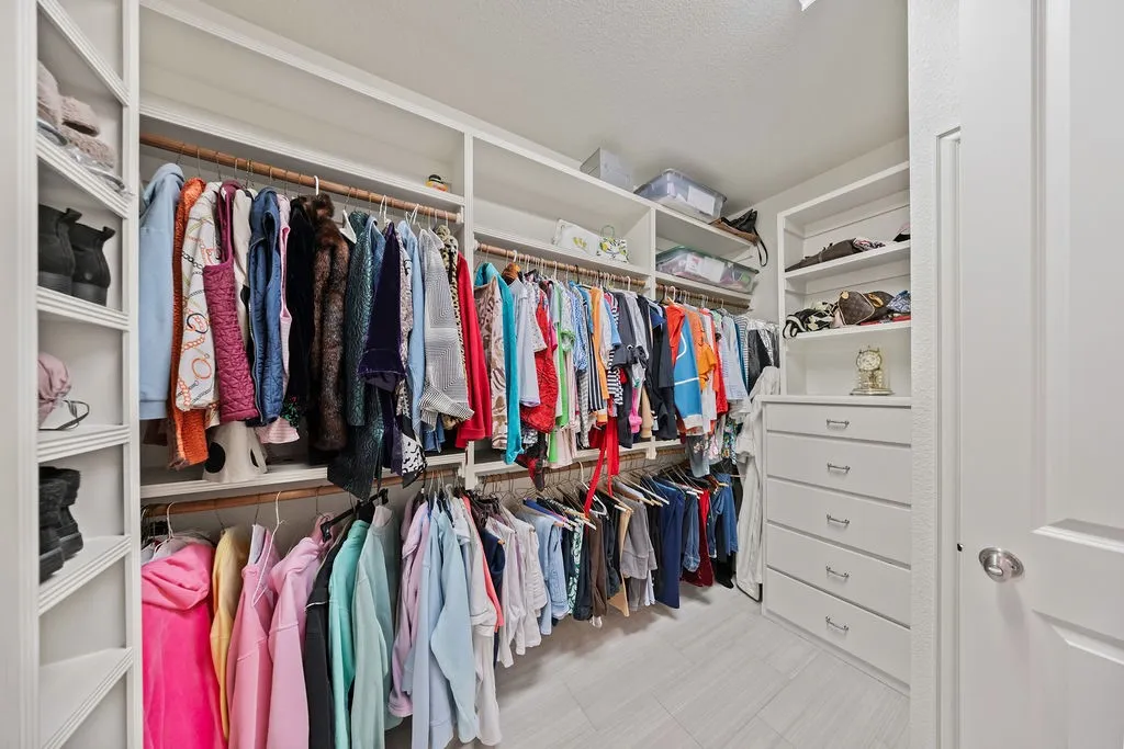 Built-in closet system featuring multiple hanging rods, open shelving, integrated drawers, and slatted shoe storage