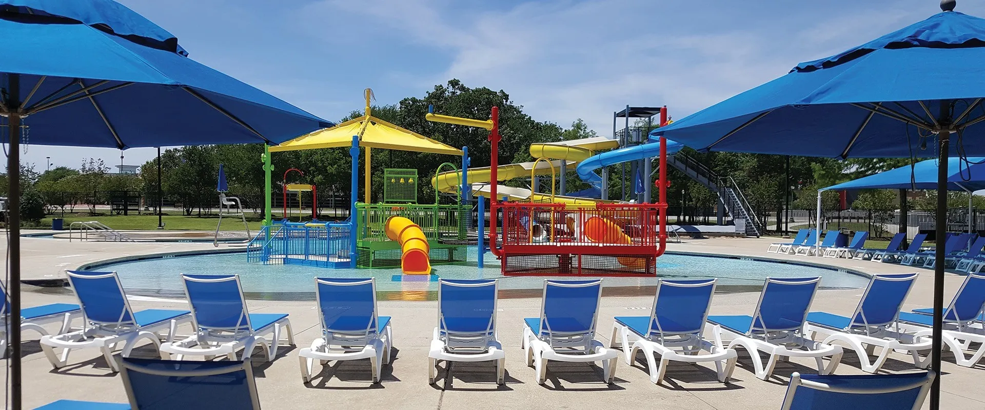 Expansive aquatic facility featuring multiple water slides, a zero-entry pool, and shaded lounge areas