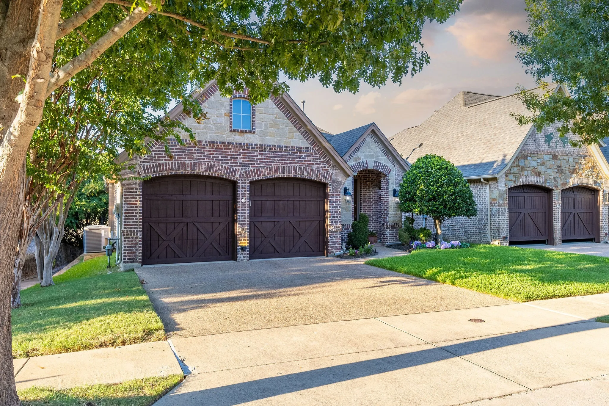 Brick and stone facade featuring arched garage doors, two-car garage, and a concrete driveway