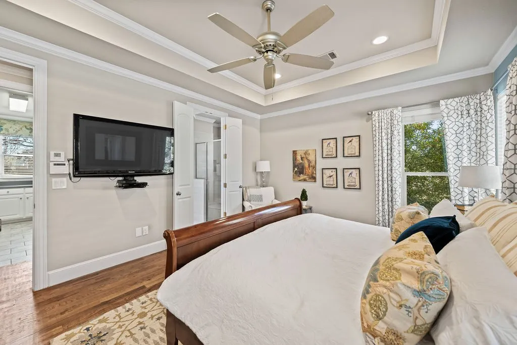 Tray ceiling with crown molding, wood-finish flooring, ceiling fan with integrated lighting, recessed lighting, and white trim throughout