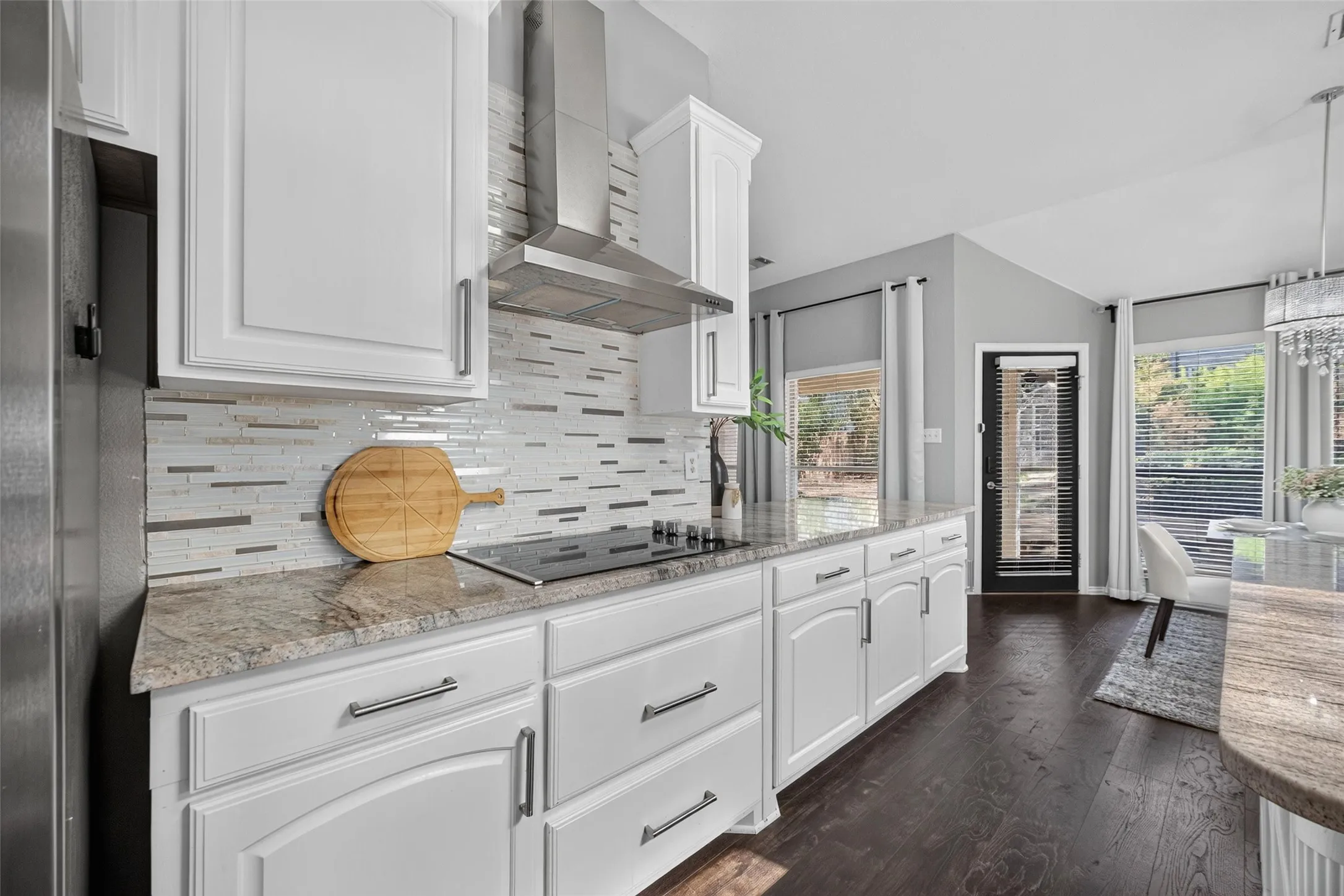 White cabinetry with brushed nickel hardware, light-toned granite countertops, and a full tile backsplash