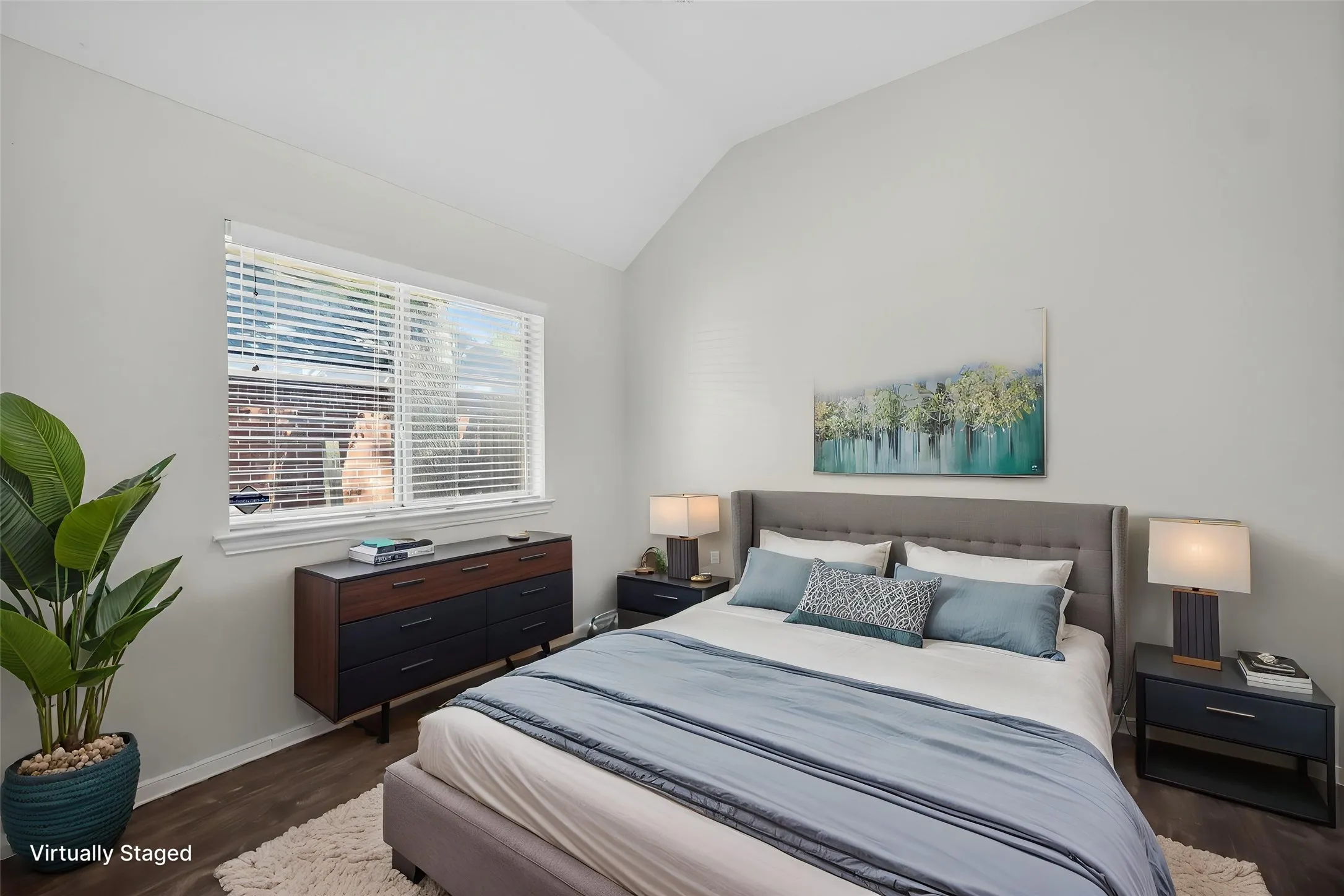 Vaulted ceiling, large window with blinds, wood-finish flooring, and light wall tones