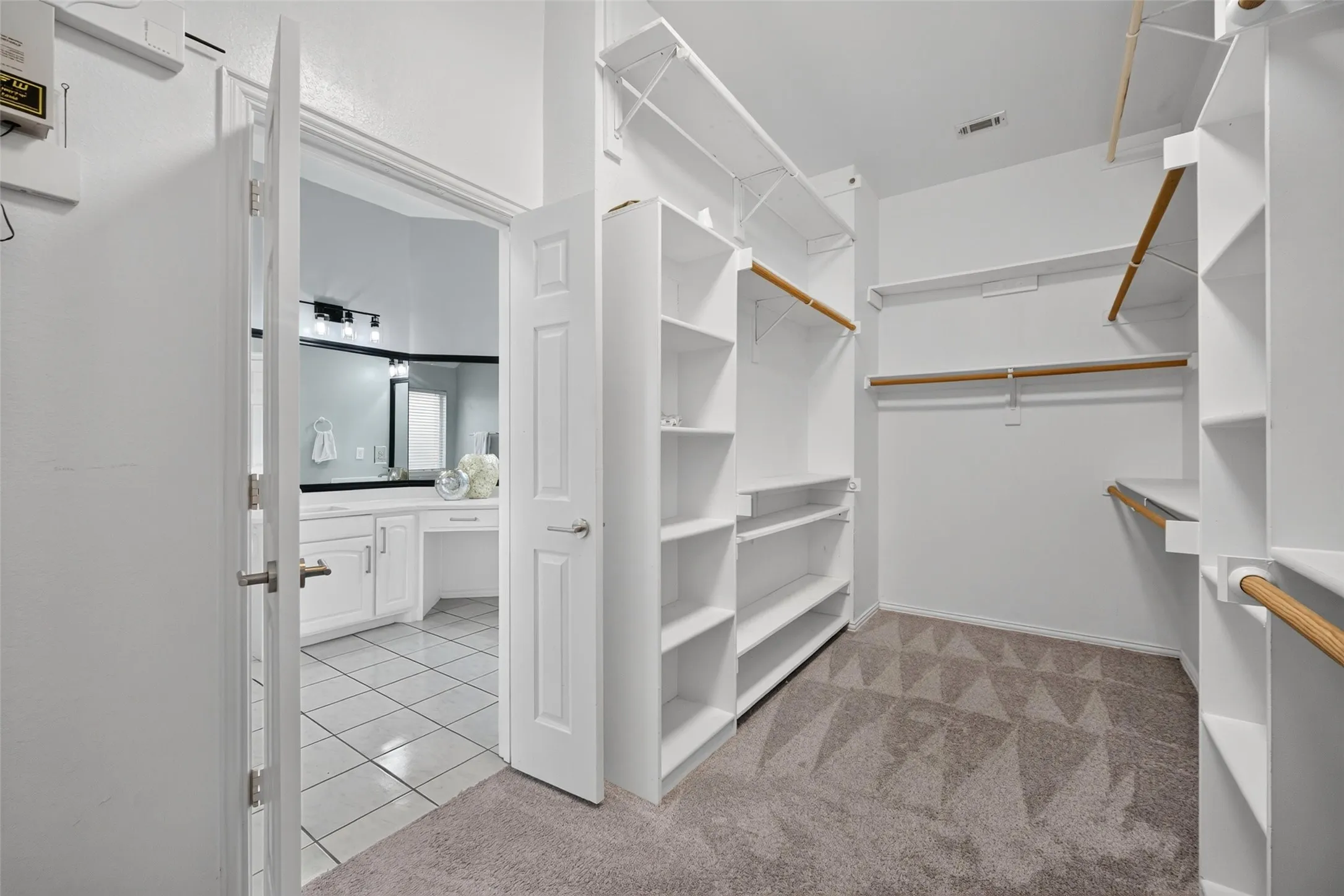 Walk-in closet featuring extensive built-in shelving, multiple hanging rods, and patterned carpet flooring