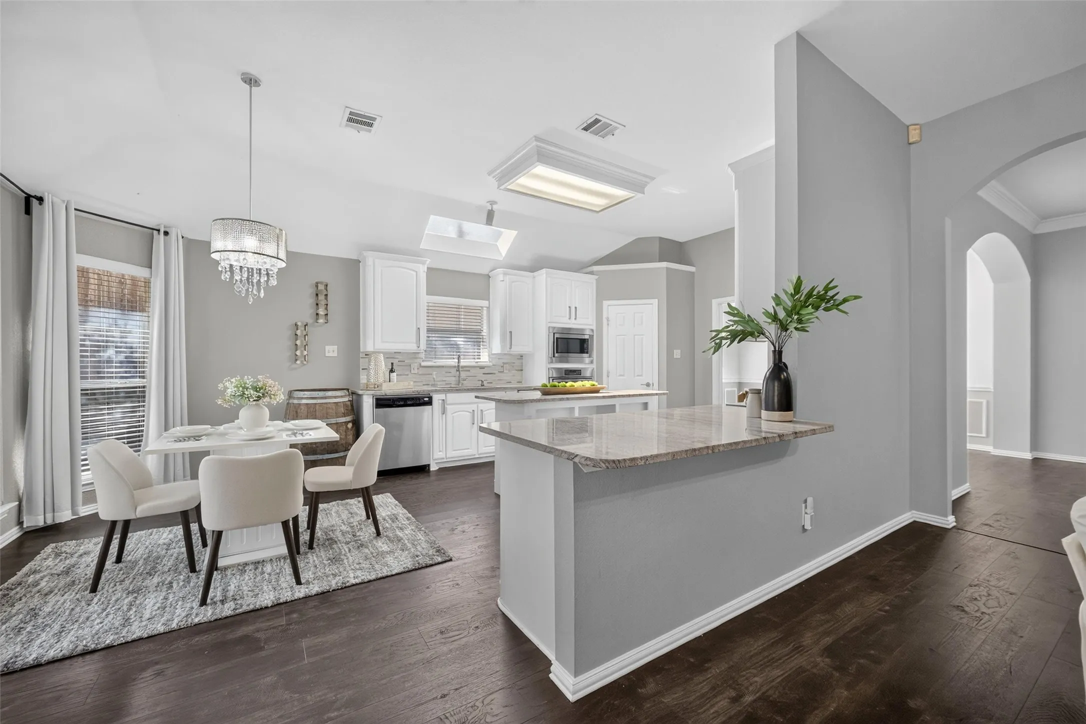Updated kitchen featuring white cabinetry, stainless steel appliances, and a granite-finish island