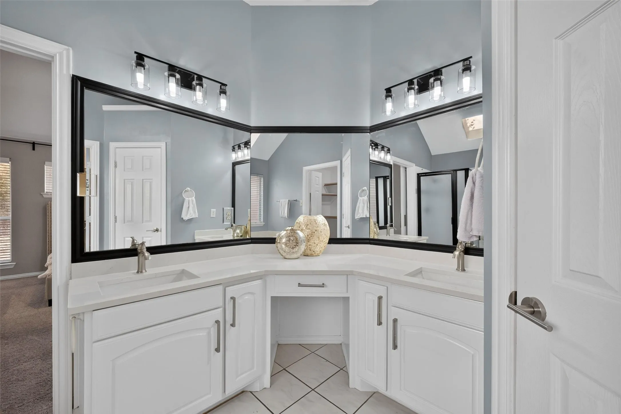 Dual vanity with integrated sinks, quartz-finish countertops, built-in makeup area, and tile flooring