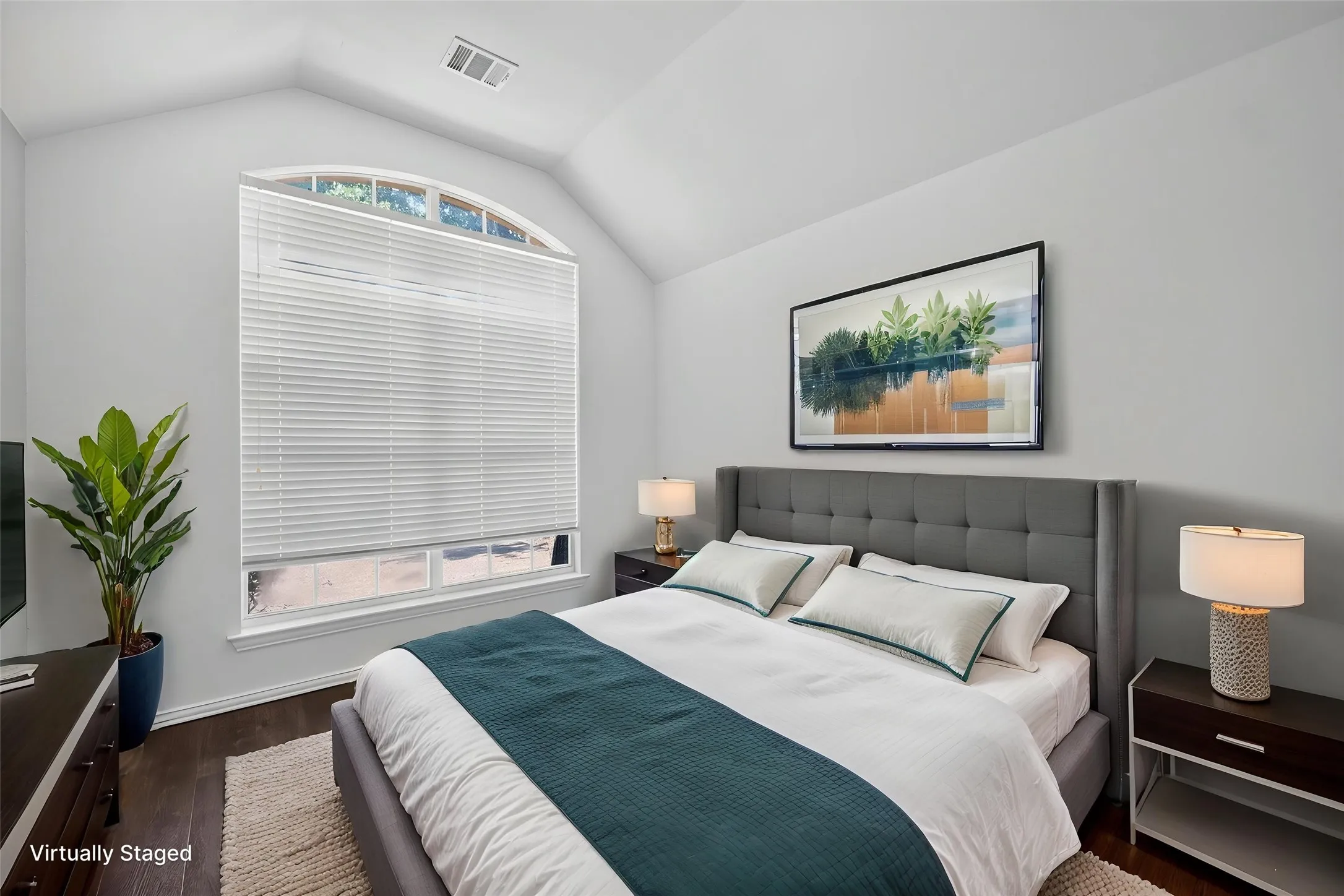 Vaulted ceiling with an arched window, featuring dark wood-finish flooring