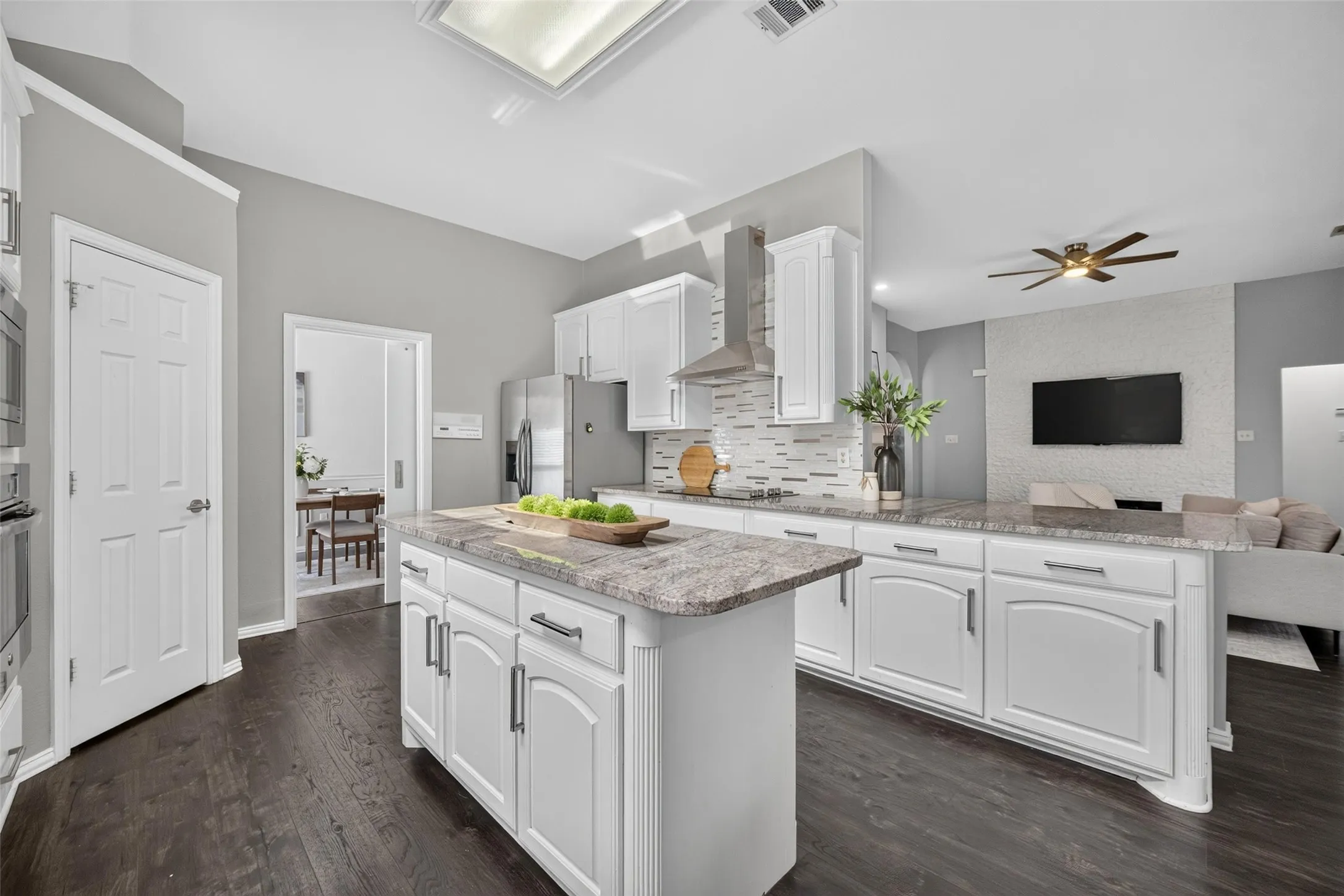 Kitchen featuring white cabinetry, stone countertops, stainless steel appliances, a tile backsplash, and wood-finish flooring