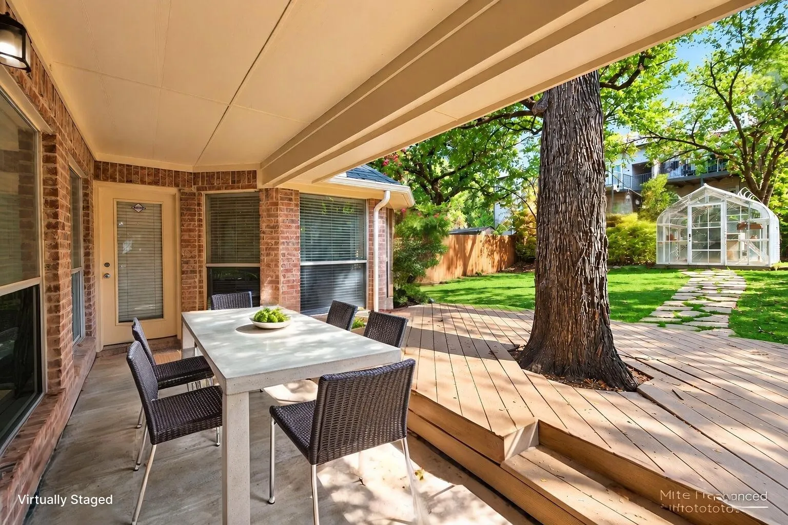 Covered patio featuring a brick exterior, outdoor wall sconce, and wood-finish decking