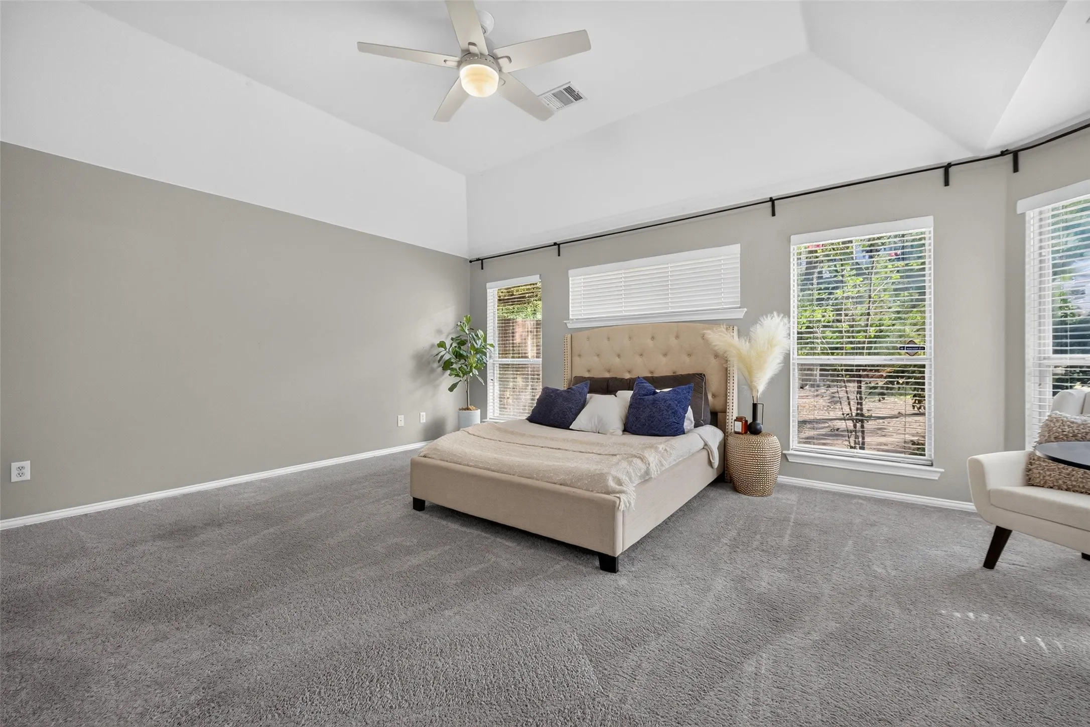 Vaulted ceiling with ceiling fan, multiple windows with blinds, and wall-to-wall carpeting