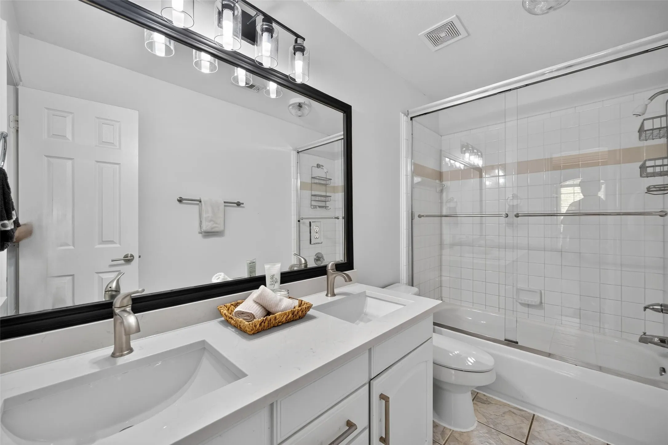 Dual vanity with integrated sinks, brushed nickel faucets, and a large framed mirror