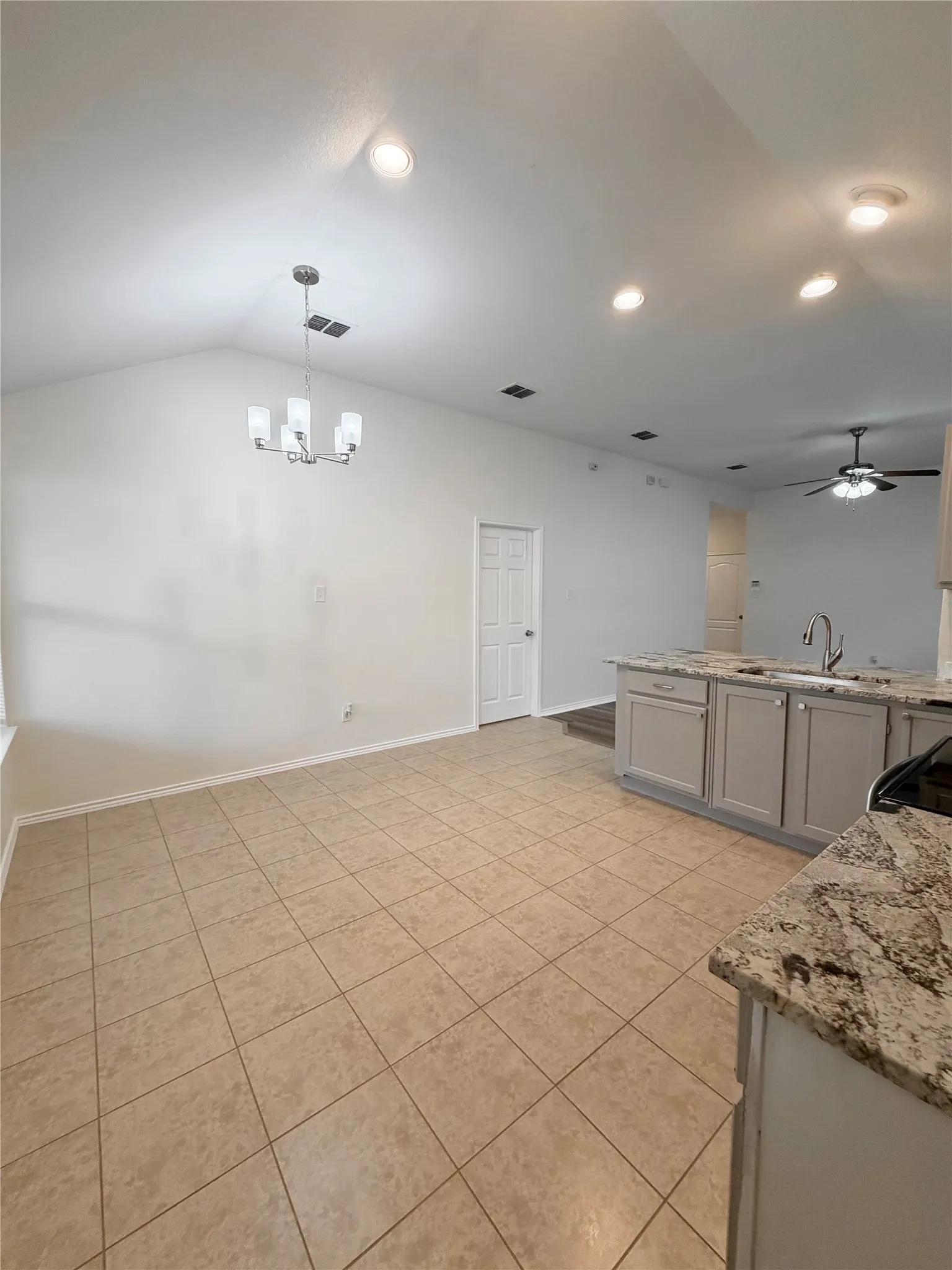 Vaulted ceilings with recessed lighting, tile flooring, and a kitchen island with stone countertops