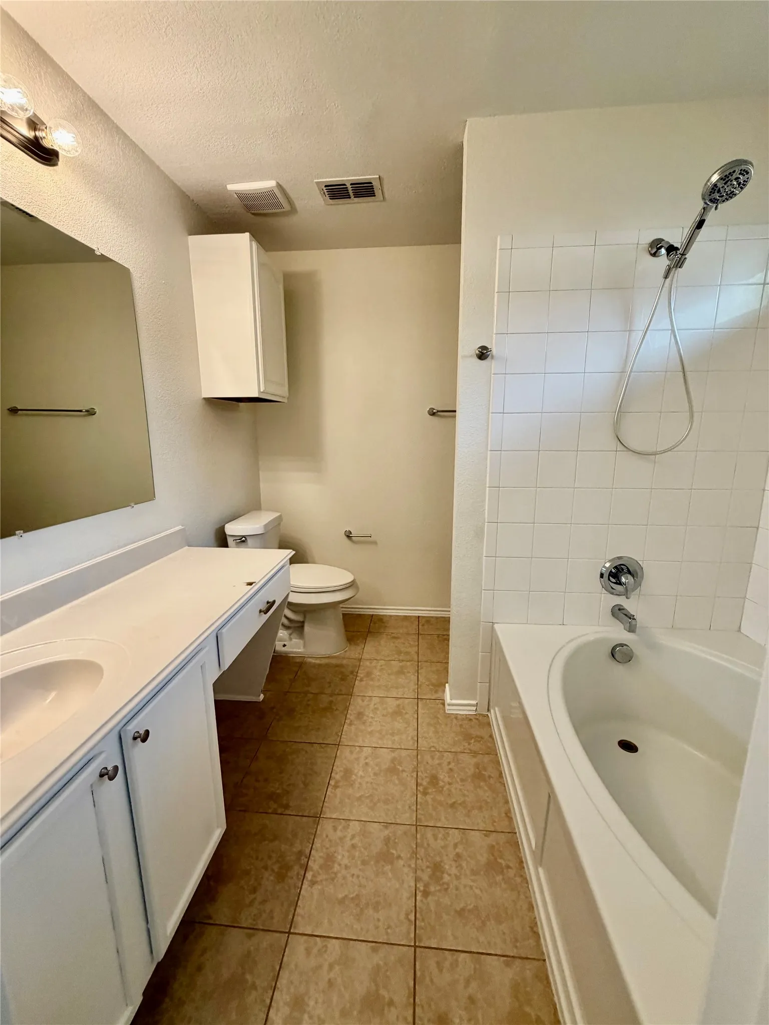 Functional bathroom featuring a single vanity, integrated sink, built-in storage cabinet, and a tiled bathtub with shower