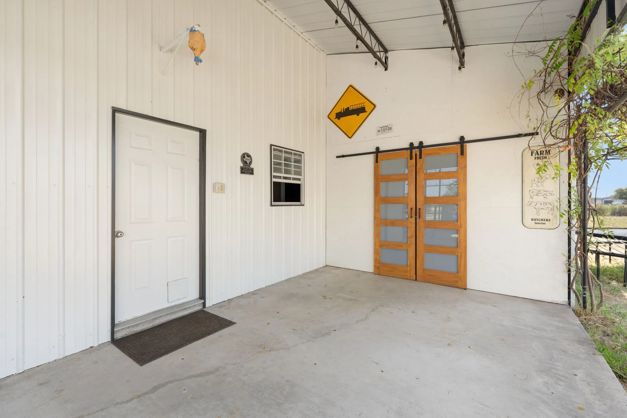 Concrete patio featuring white panel siding, a white entry door, and a multi-pane window