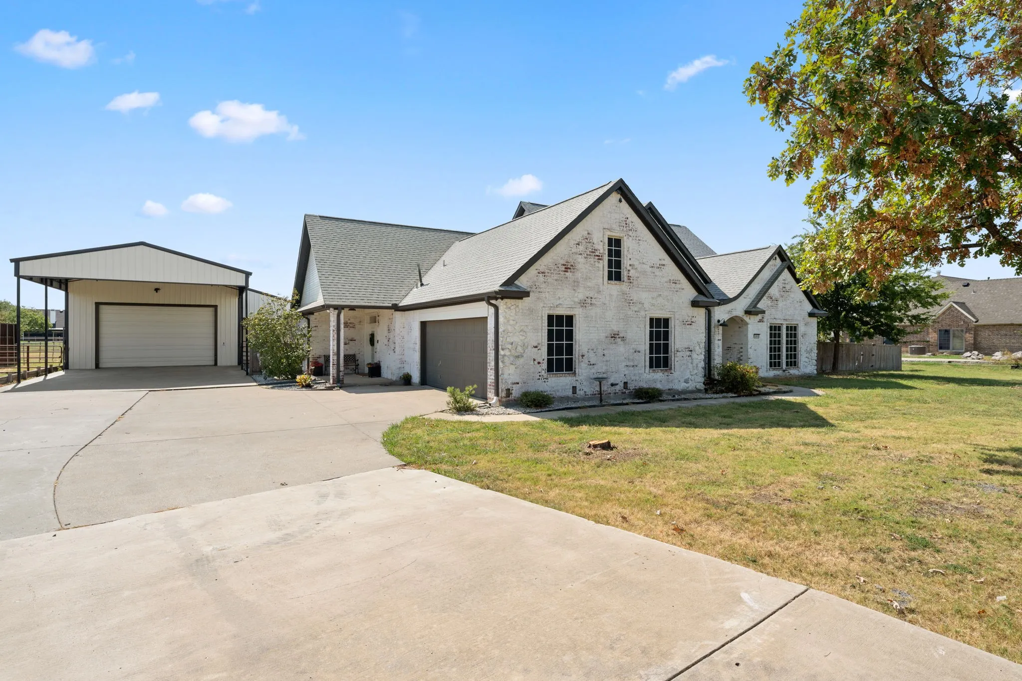 Brick exterior with dark trim accents, attached garage, and detached garage with covered parking