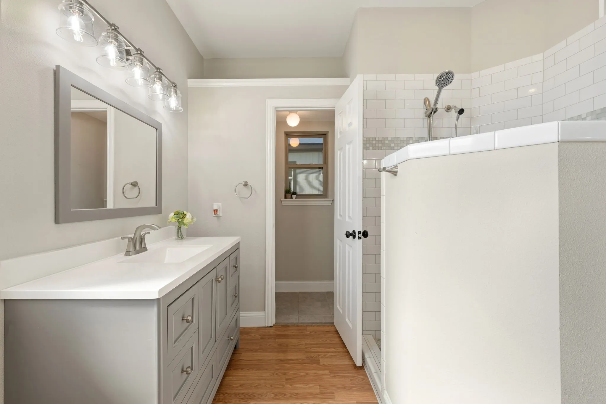 Wood-finish flooring leading to a vanity with a white countertop and rectangular sink