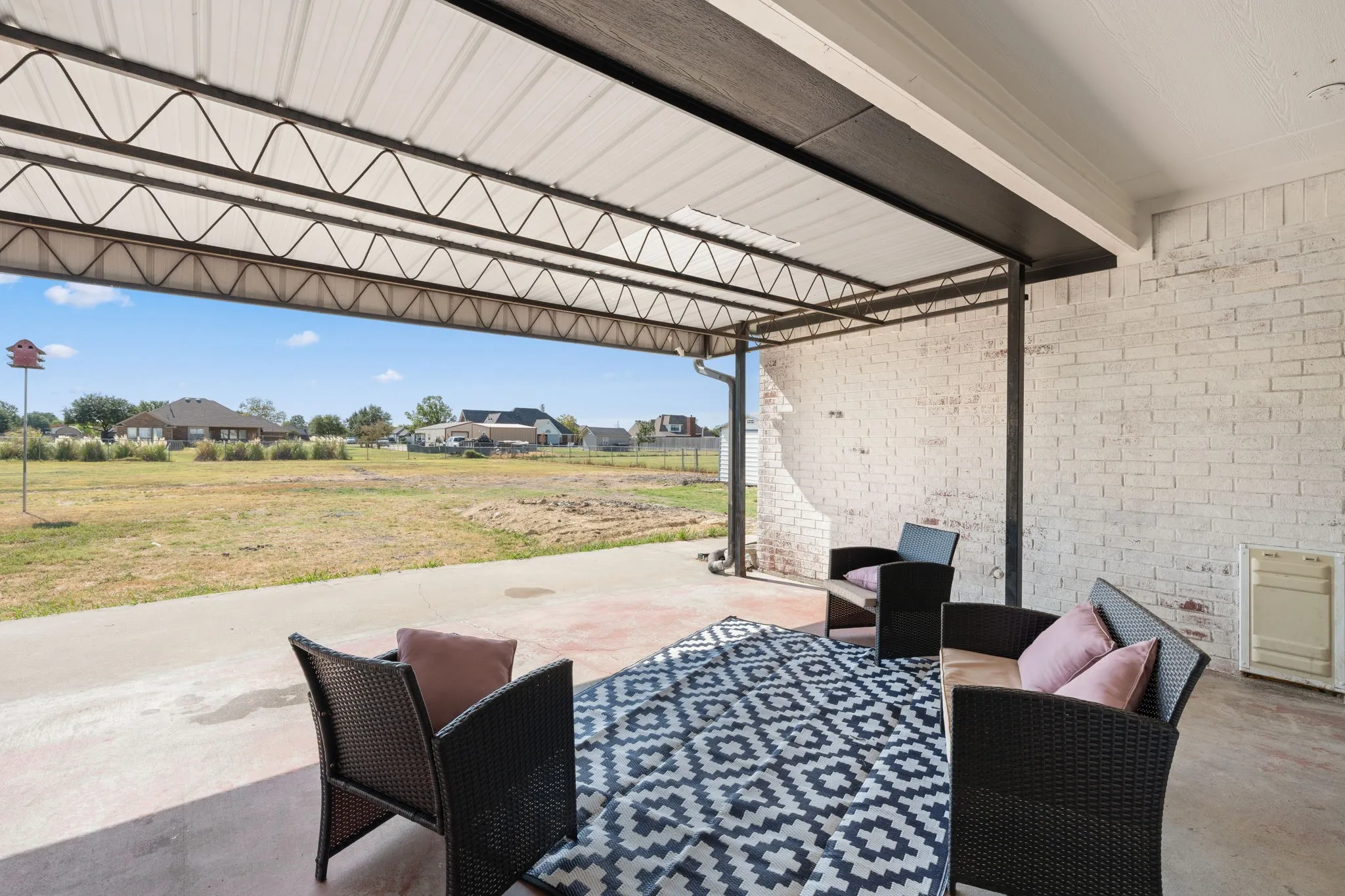Covered patio featuring a concrete slab and white-painted brick wall