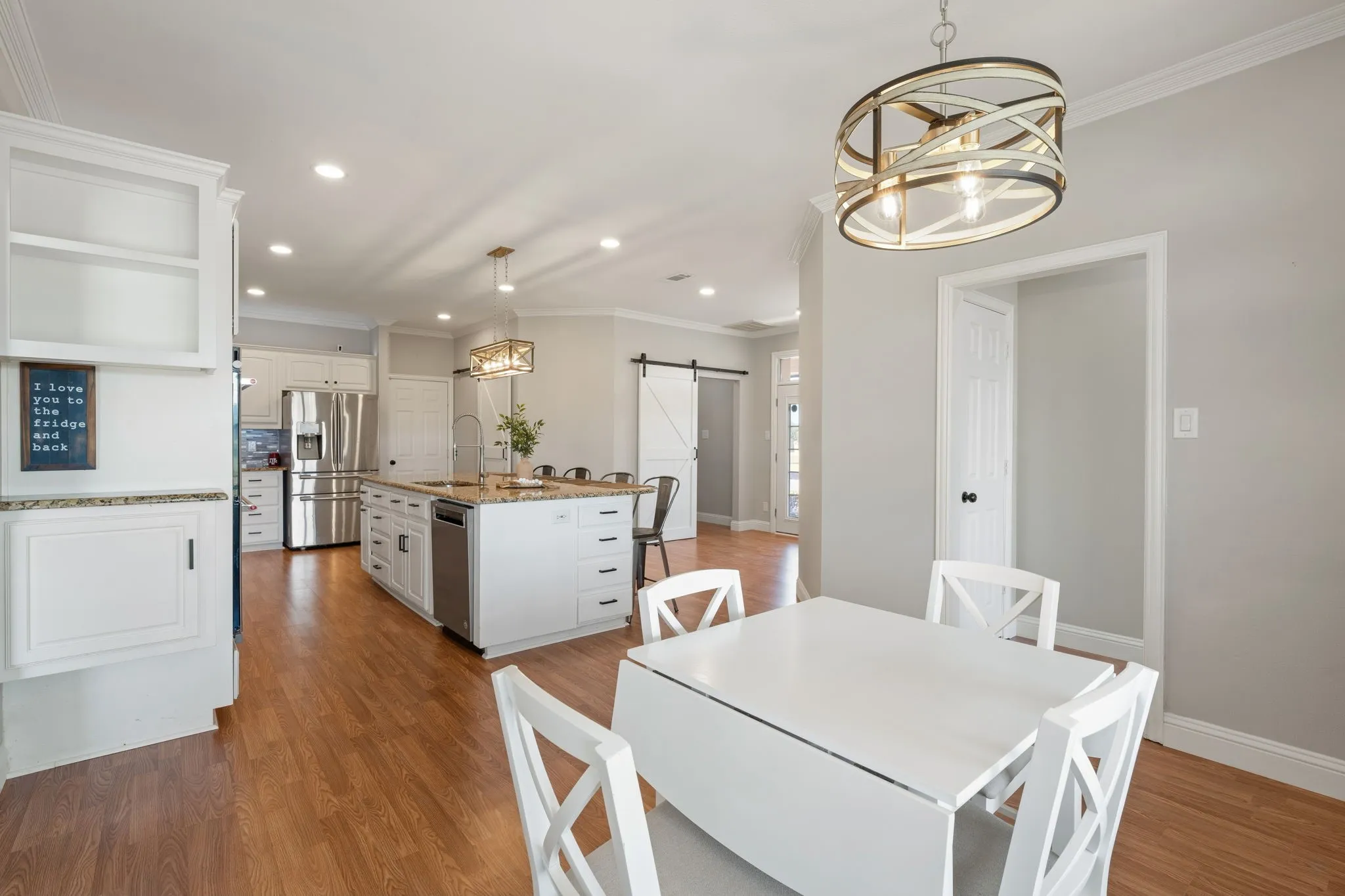 Spacious kitchen with a central island, stainless steel appliances, and white cabinetry