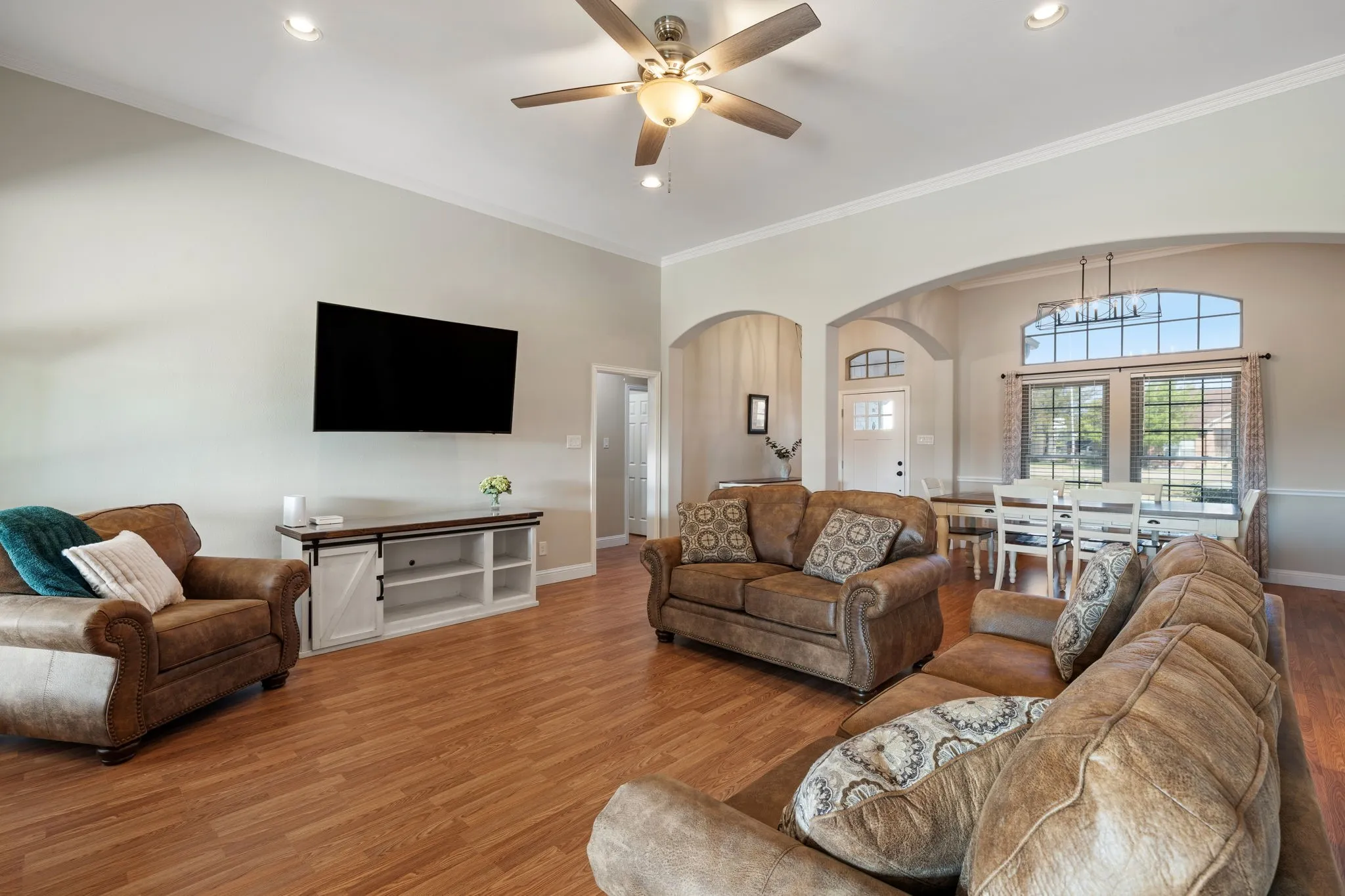 Vaulted ceiling with recessed lighting and a ceiling fan, wood-finish flooring, and arched doorways