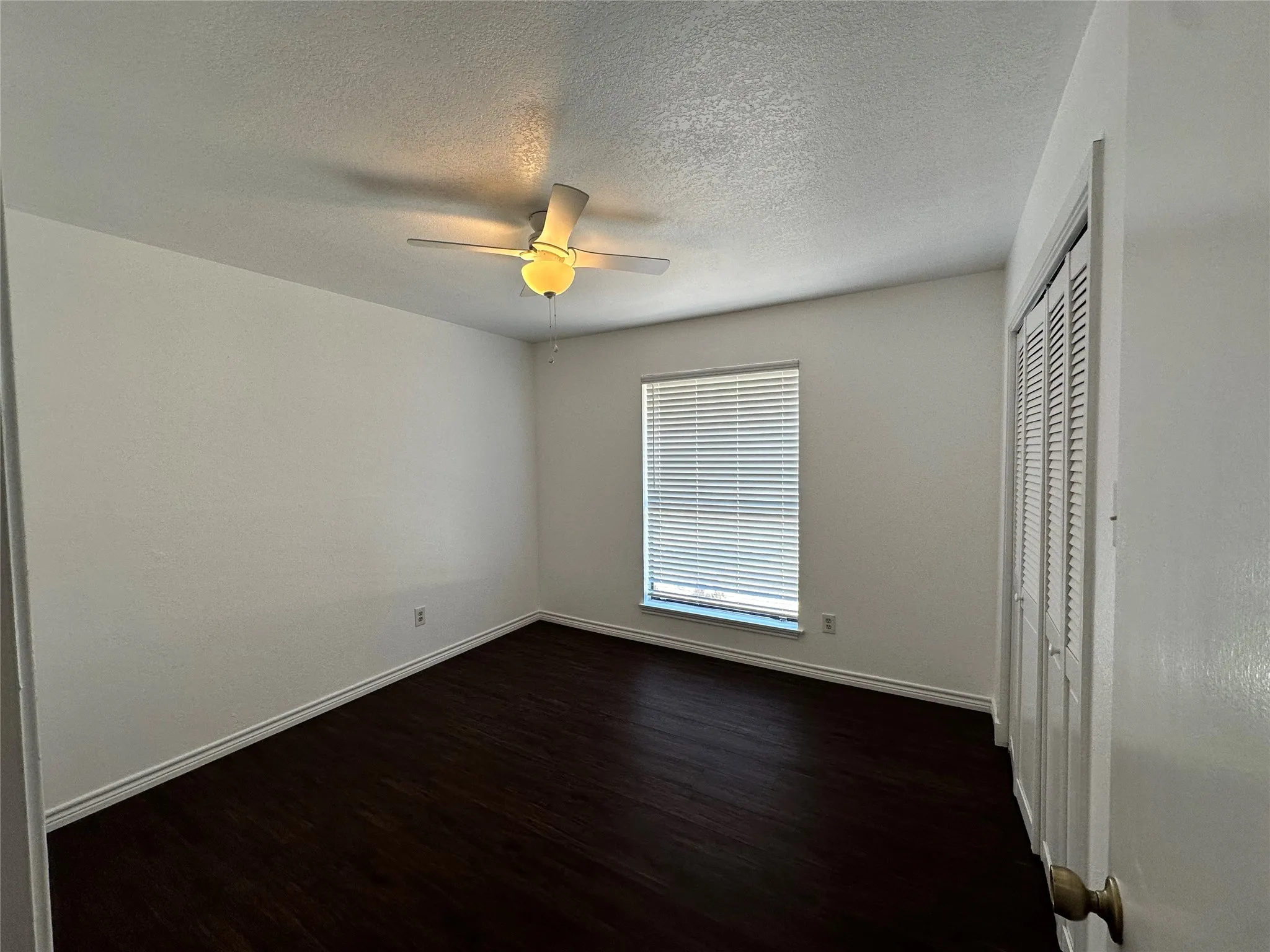 Wood-finish flooring, white walls, and a ceiling fan with integrated lighting
