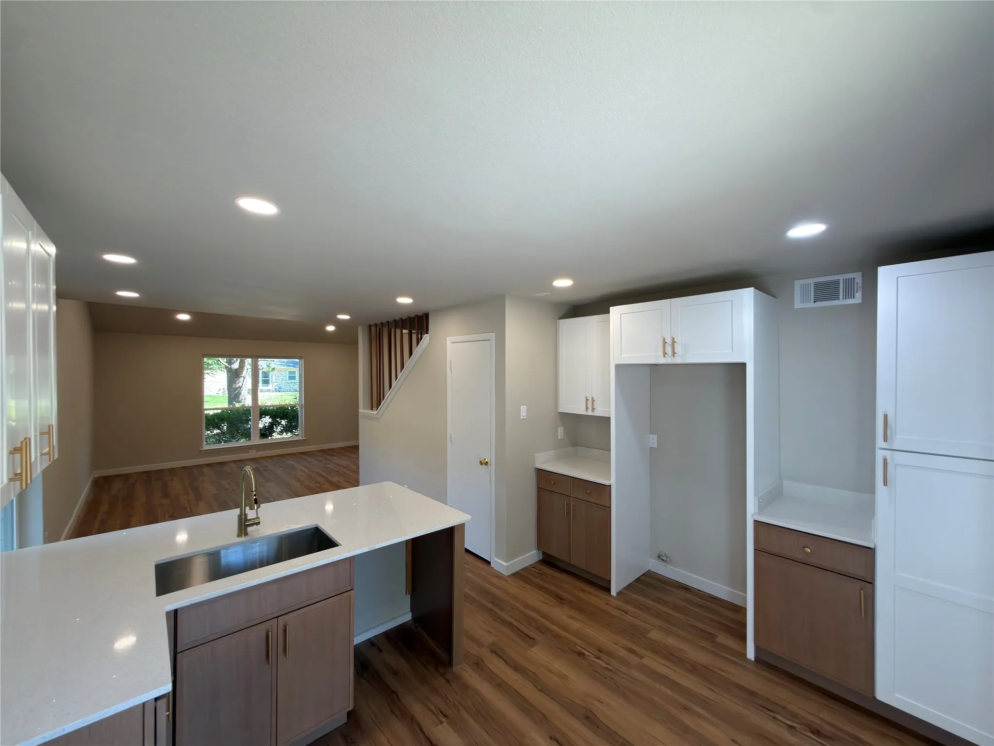 Kitchen featuring white upper cabinetry, wood-finish lower cabinetry, white countertops, and a stainless steel sink with a gooseneck faucet