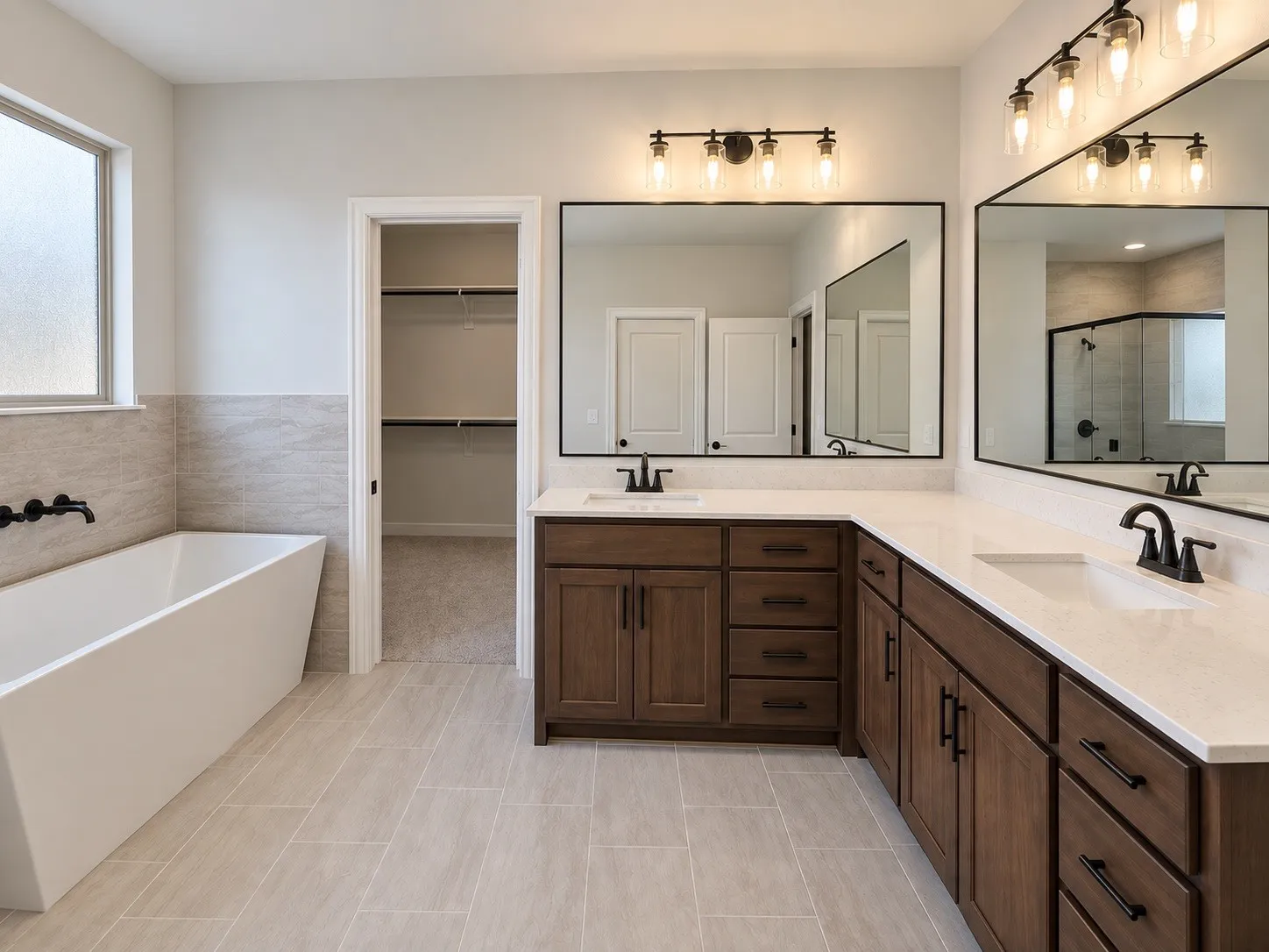 Freestanding tub with a wall-mounted faucet, dual vanities with white countertops, dark wood-finish cabinetry, and large framed mirrors