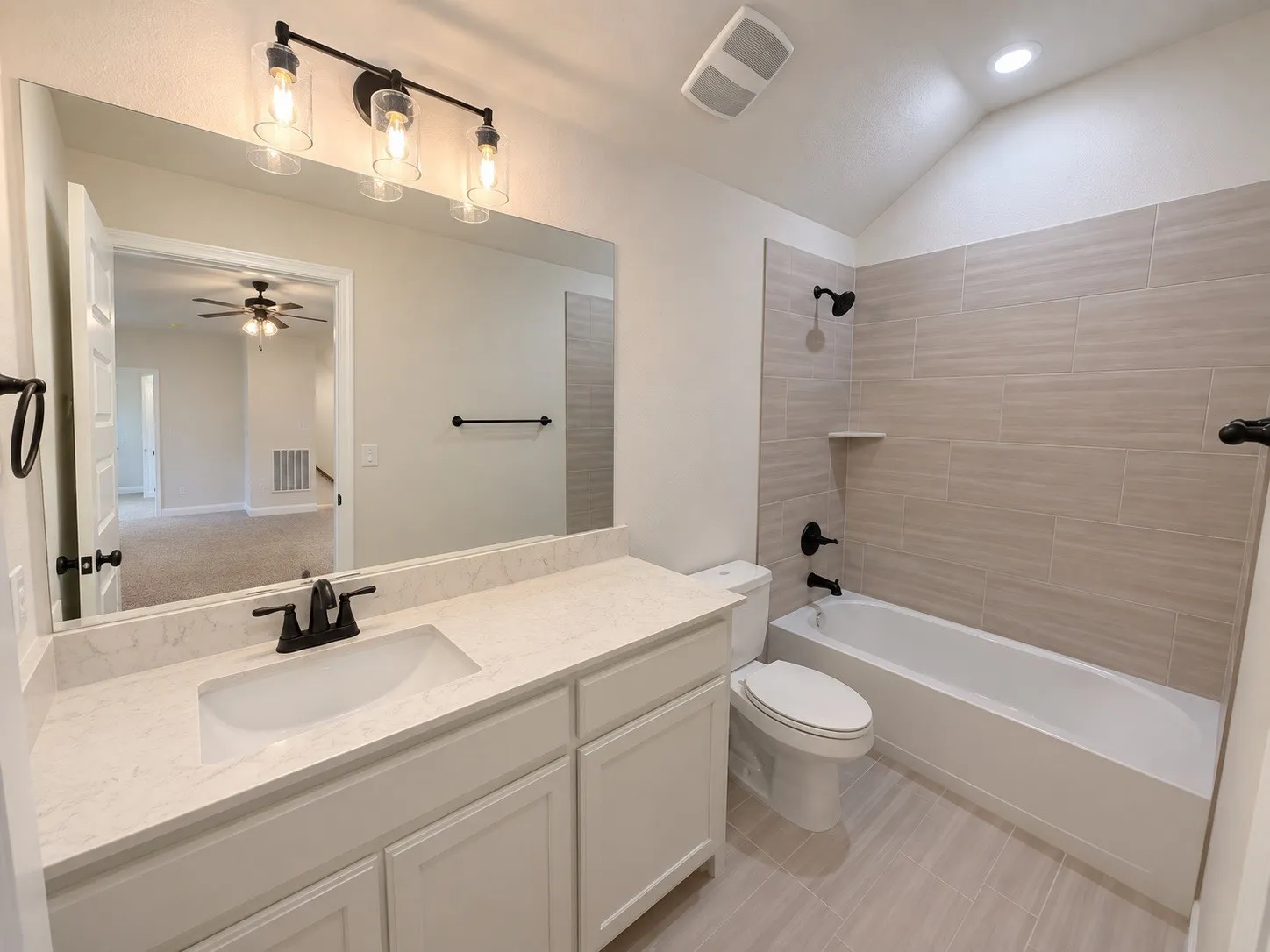 Bathroom featuring a single vanity with stone-finish countertop, undermount sink, and matte black fixtures