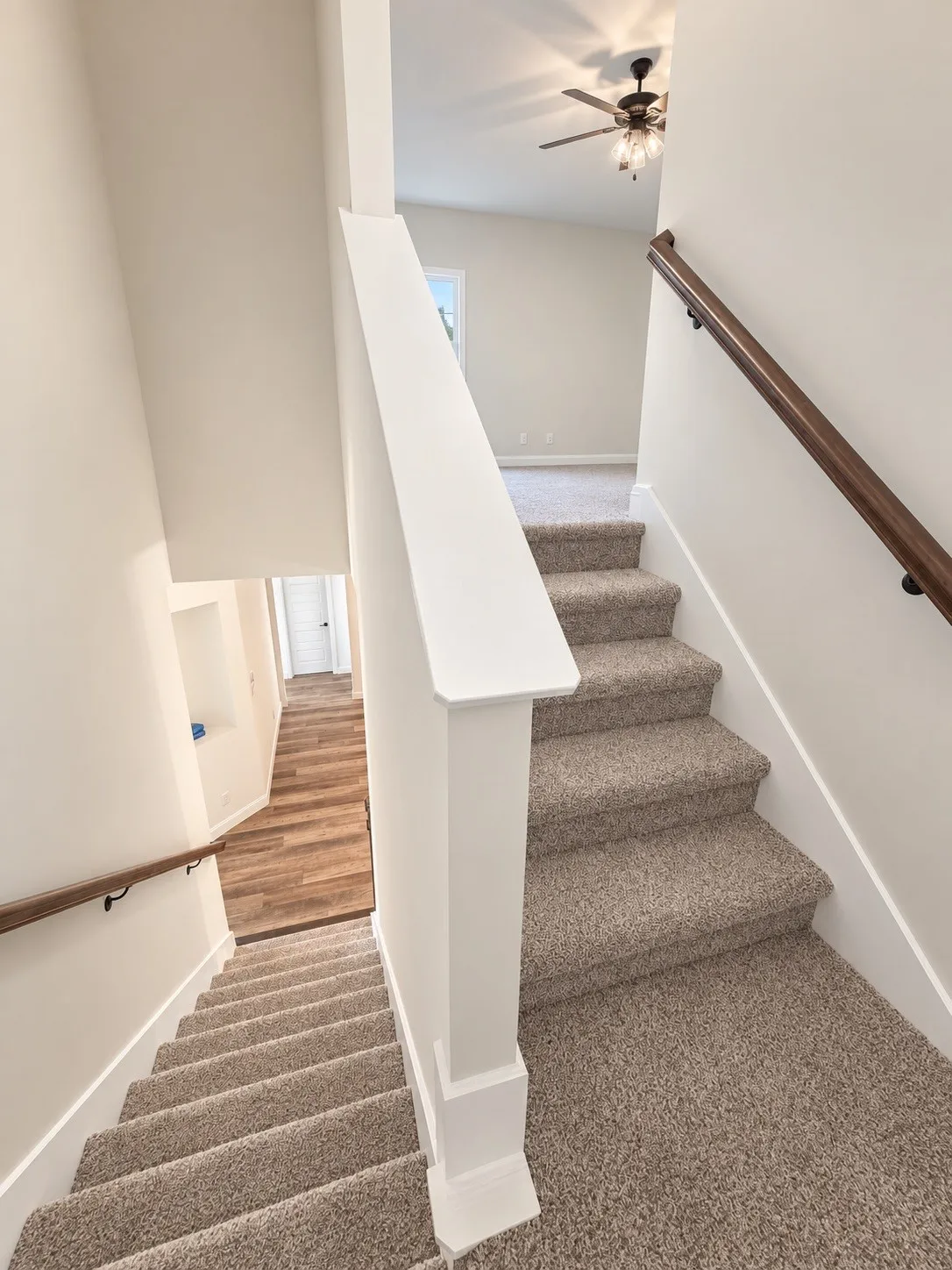 Carpeted staircase with wood-finish handrails