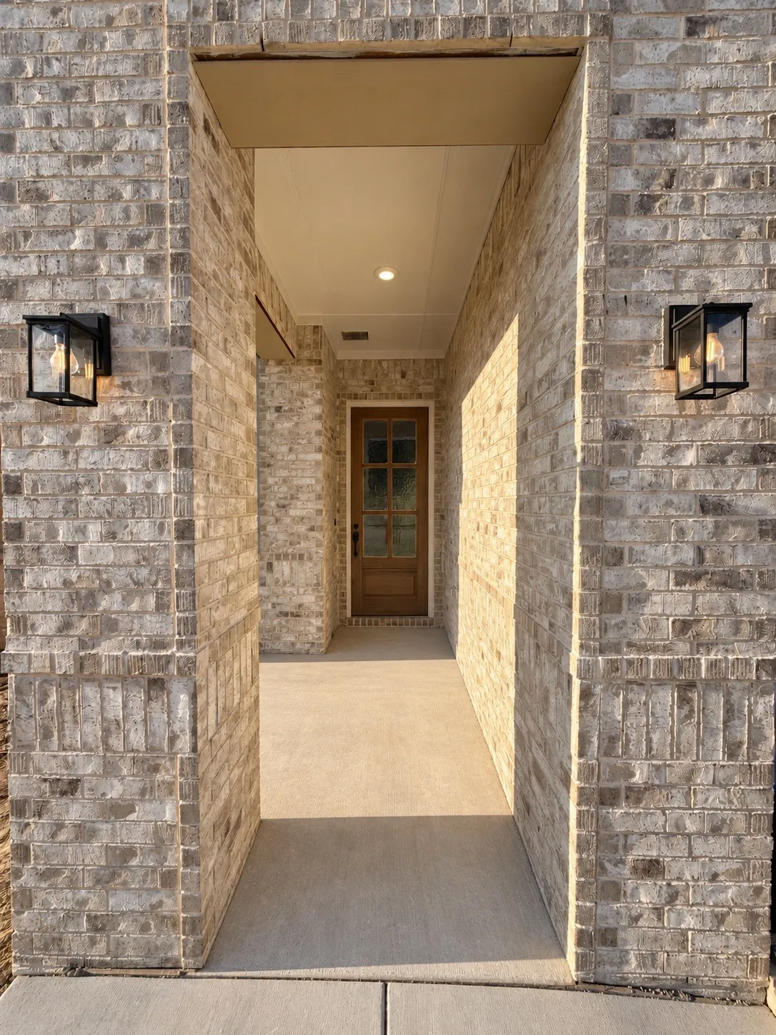 Brick exterior with a covered entry, recessed ceiling lighting, and a paneled entry door with glass inserts