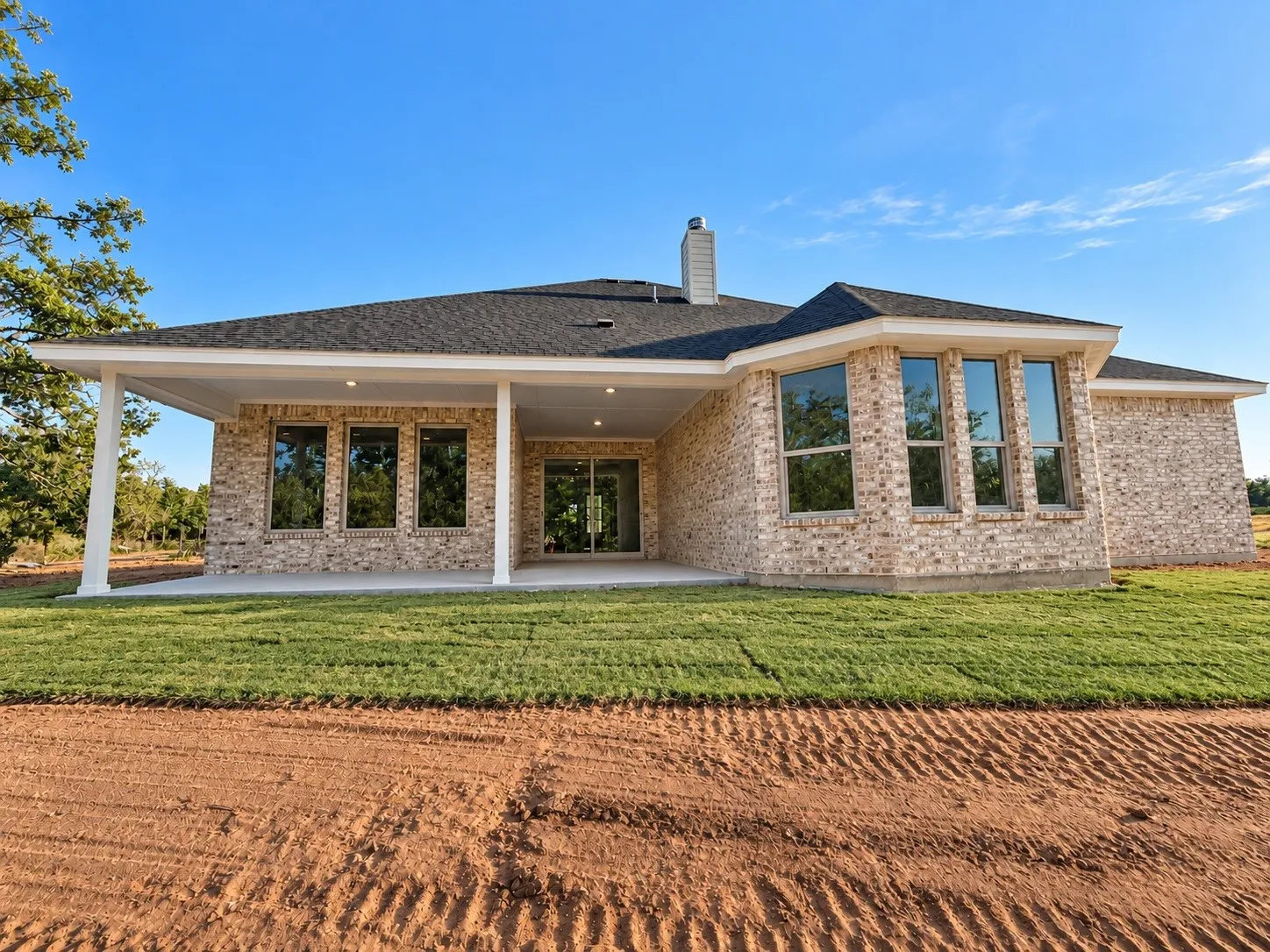 Brick exterior with a covered patio, recessed lighting, and multiple large windows