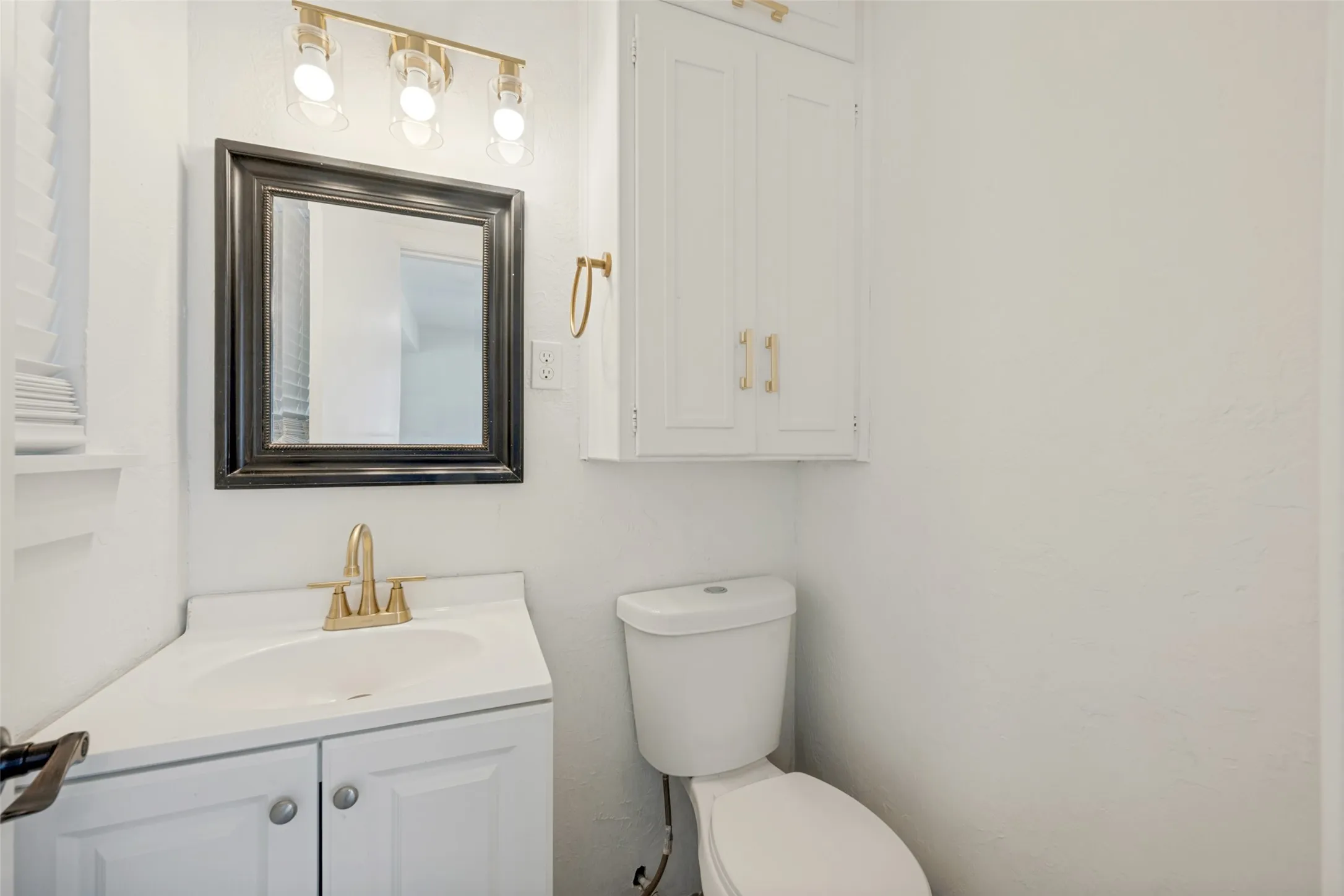 Corner vanity with integrated sink, gold-finish faucet, and coordinating overhead lighting