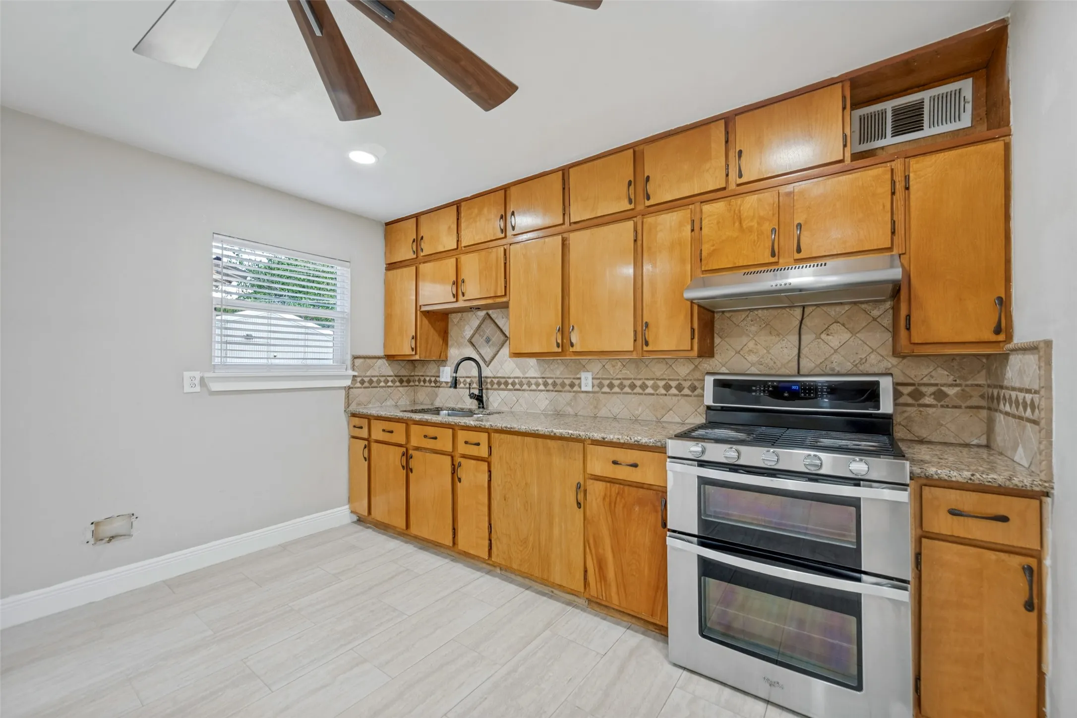 Wood-finish cabinetry paired with granite-style countertops and a decorative tile backsplash