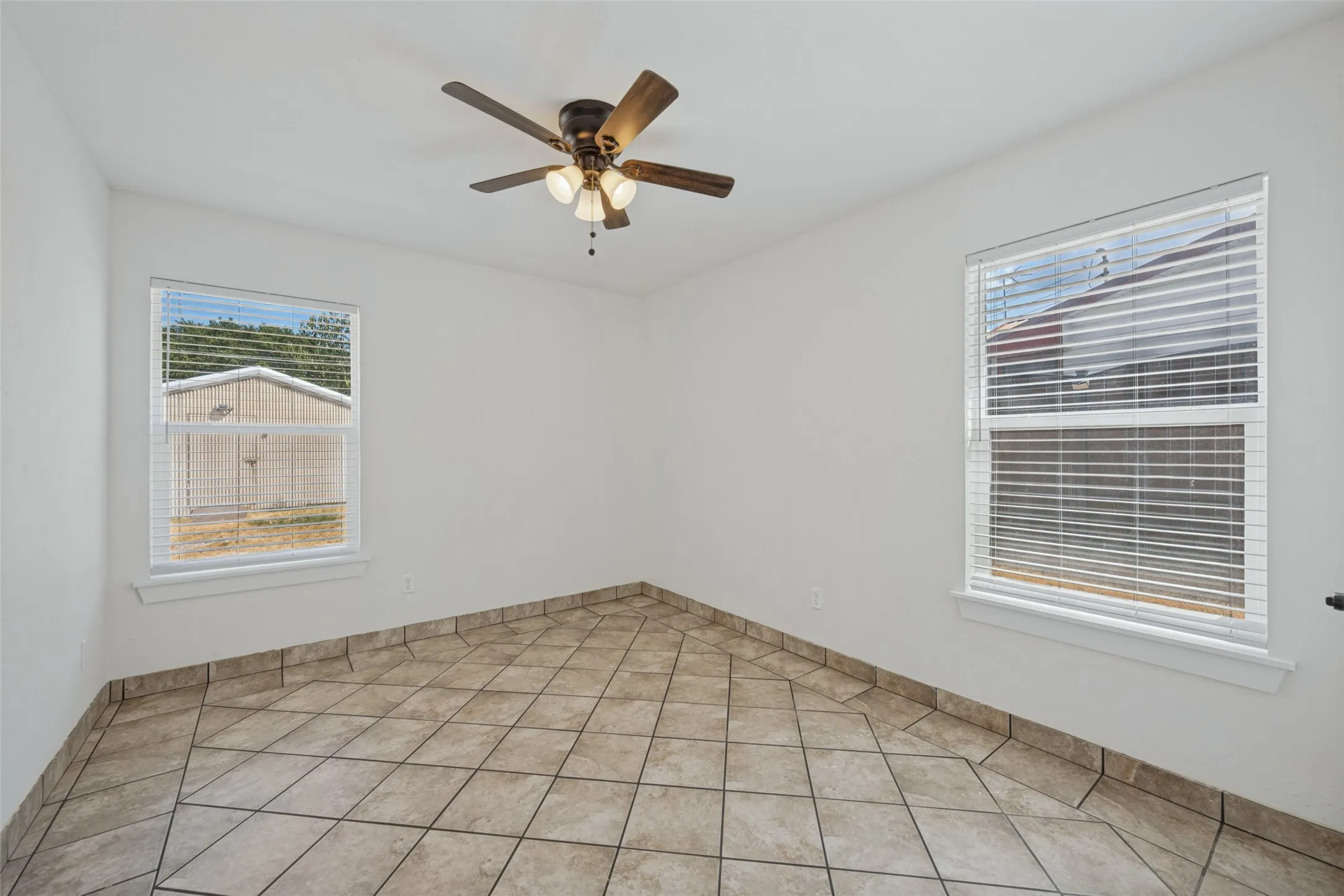 Two windows with blinds, ceiling fan with integrated lighting, and tile flooring